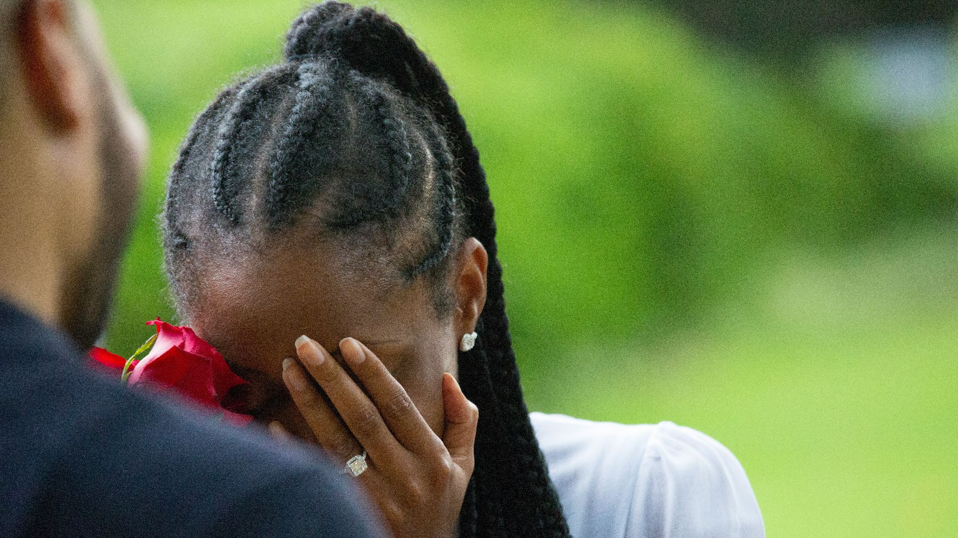 woman wearing white shirt holding rose covering face