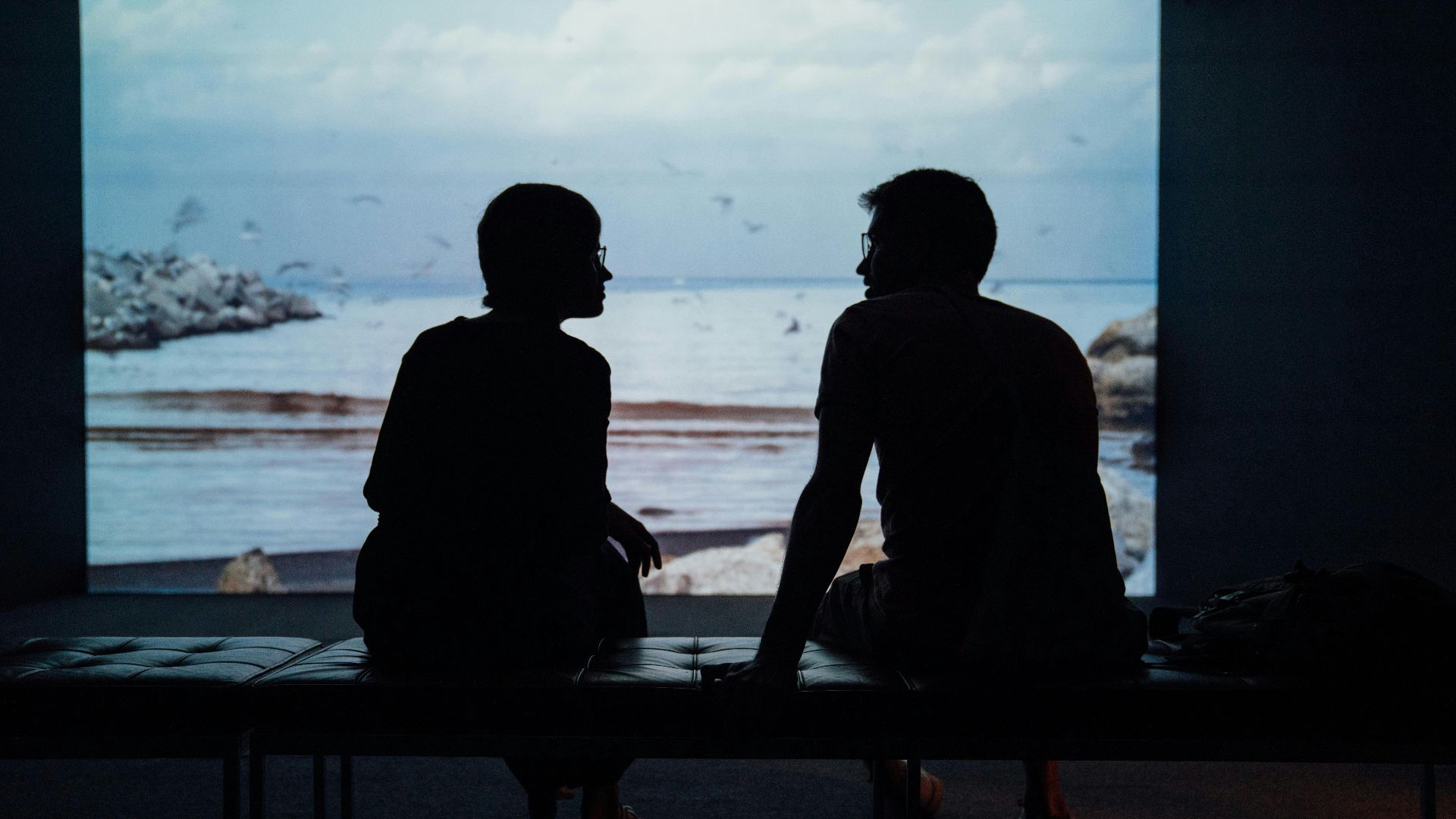silhouette of man and woman sitting on ottoman