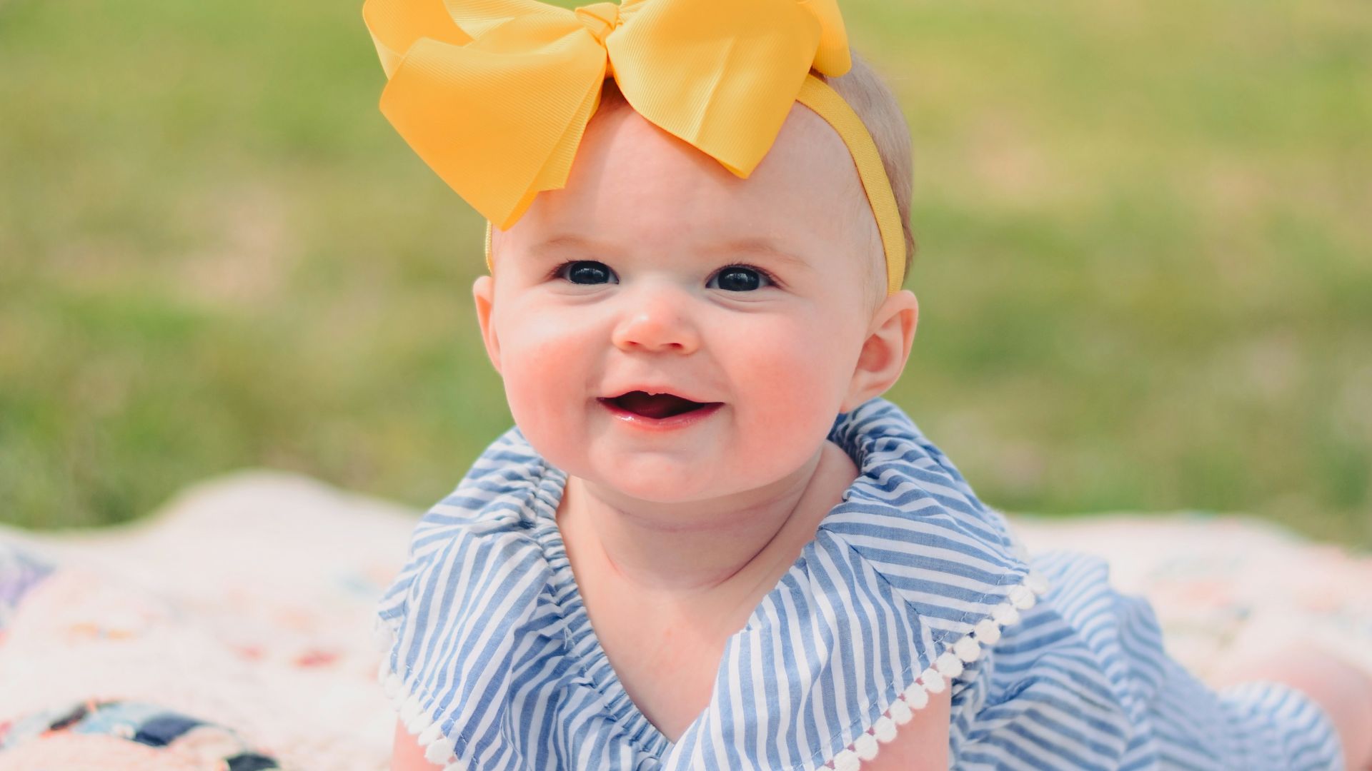 smiling baby lying forward on pink textile