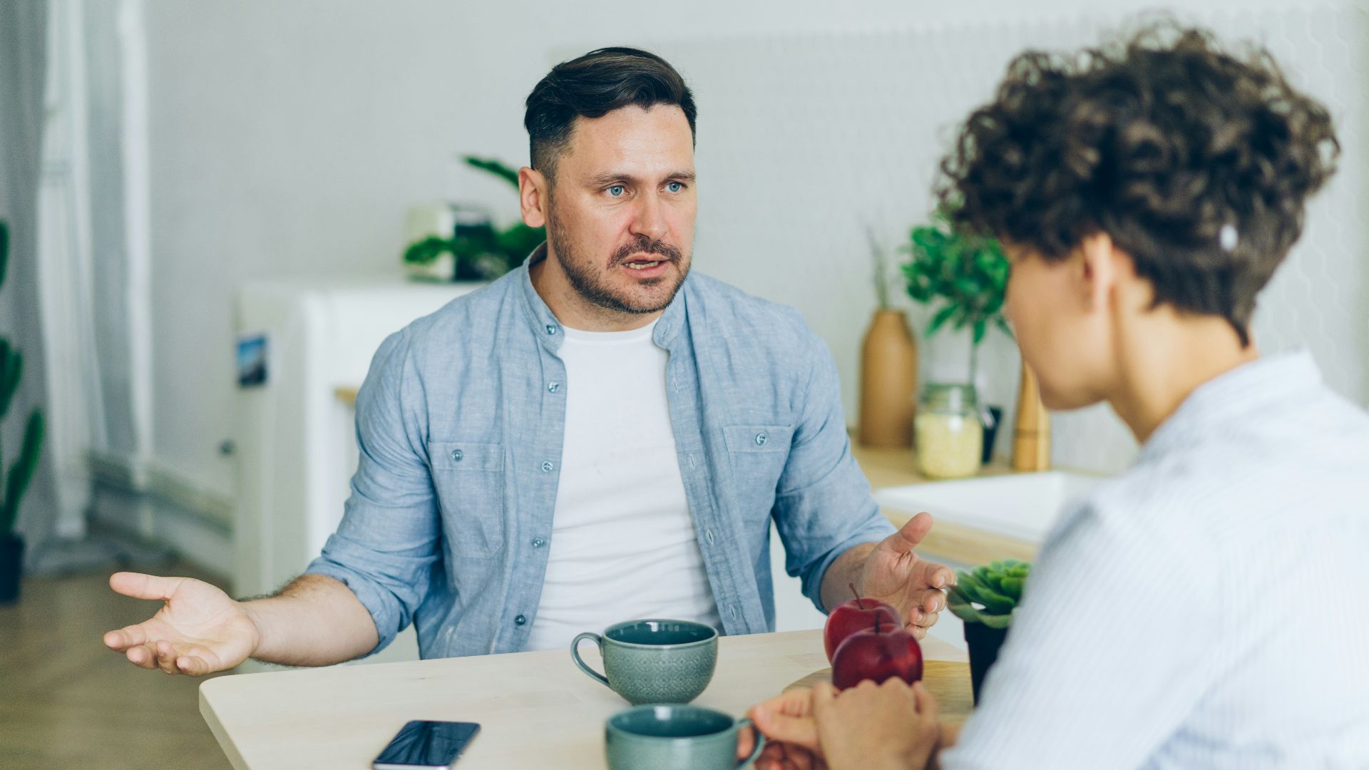a man sitting at a table talking to a woman