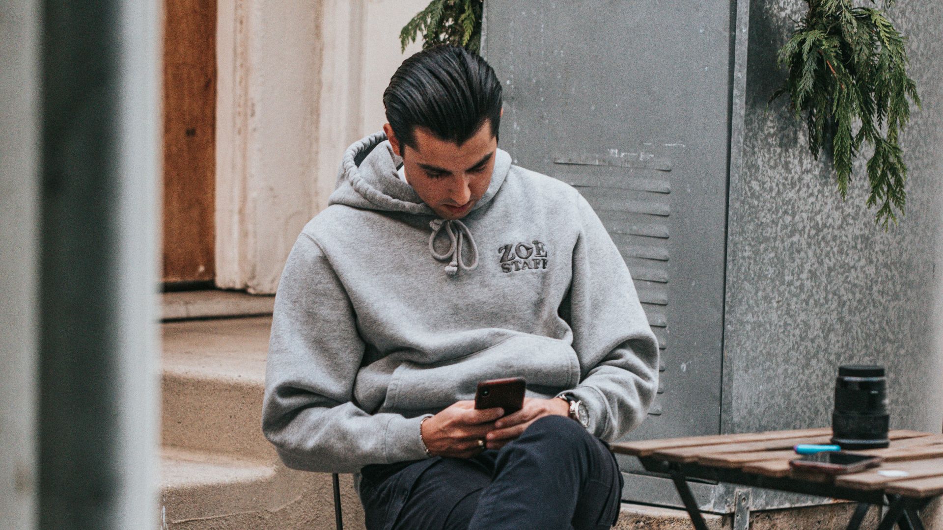 man in gray sweater sitting on brown wooden folding table