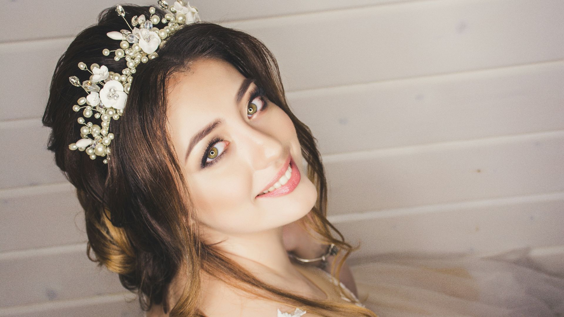 woman with white floral headdress beside white wall