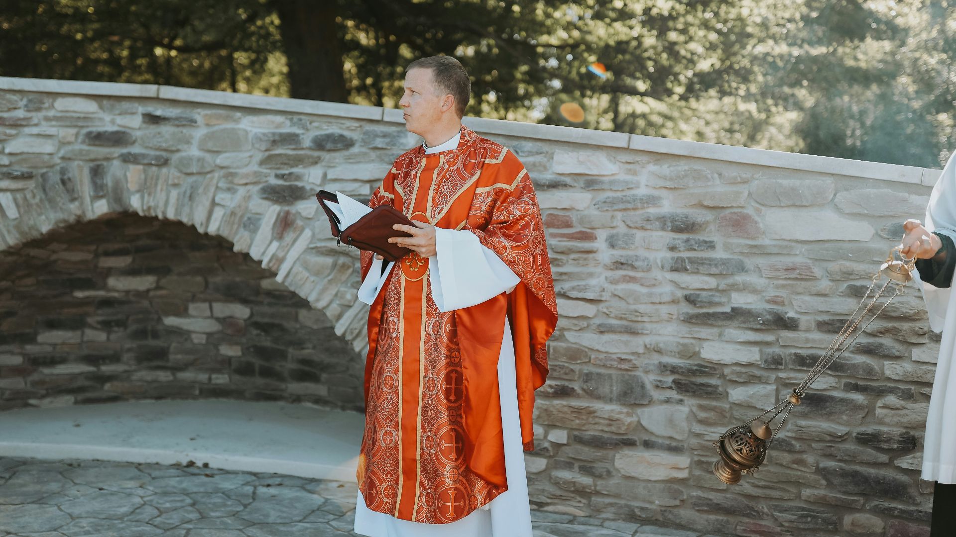 man in red and white robe standing on gray concrete floor during daytime