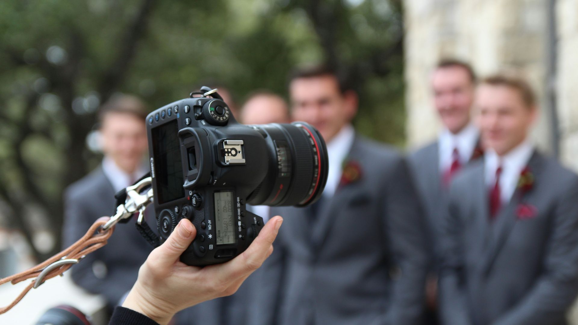 man in black suit holding black nikon dslr camera