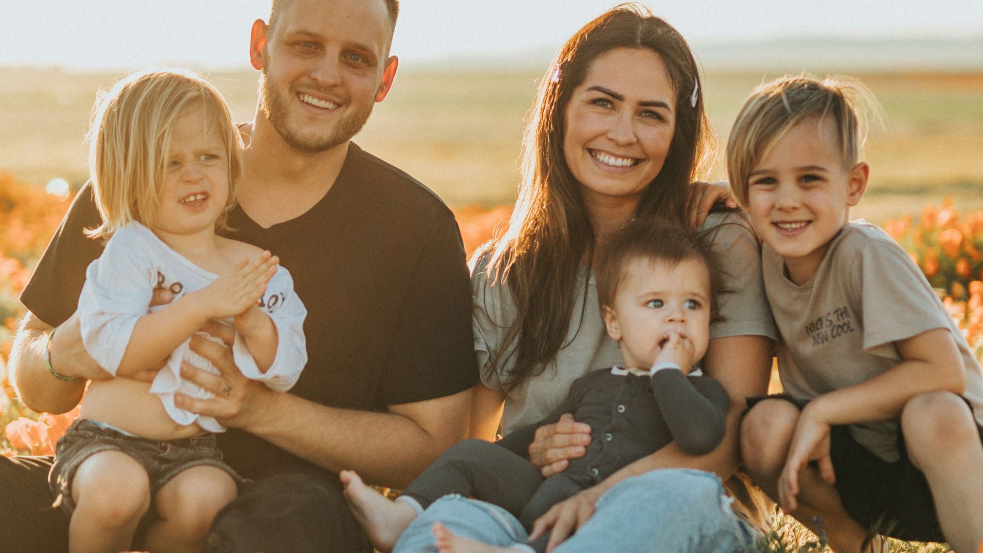 3 women and 2 men sitting on green grass field during daytime