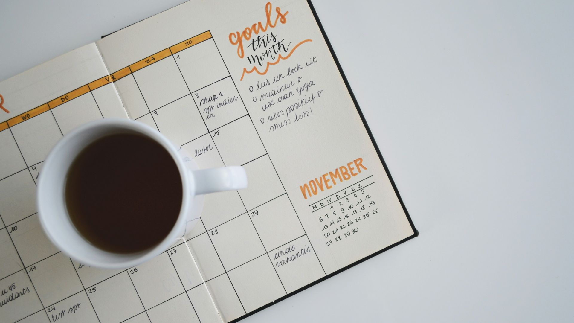 white ceramic mug with coffee on top of a planner