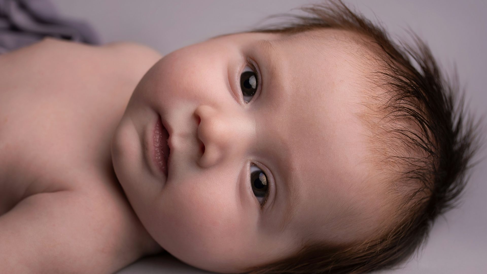 baby lying on white bed