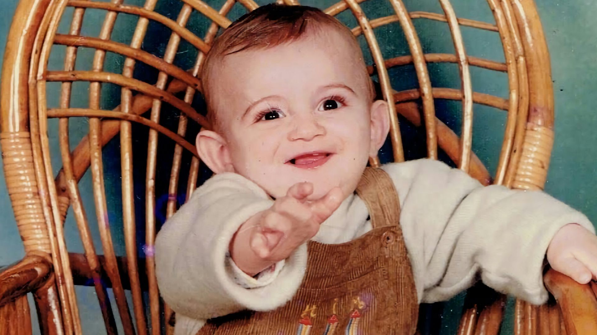 a baby is sitting in a wicker chair
