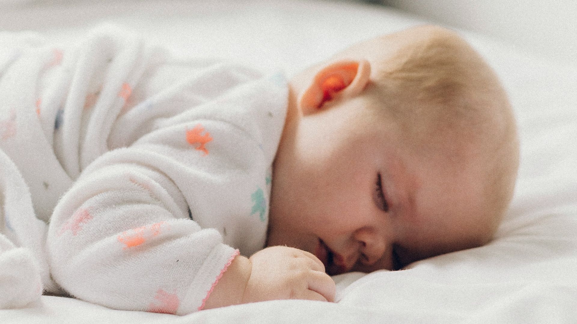 photo of baby laying on bed