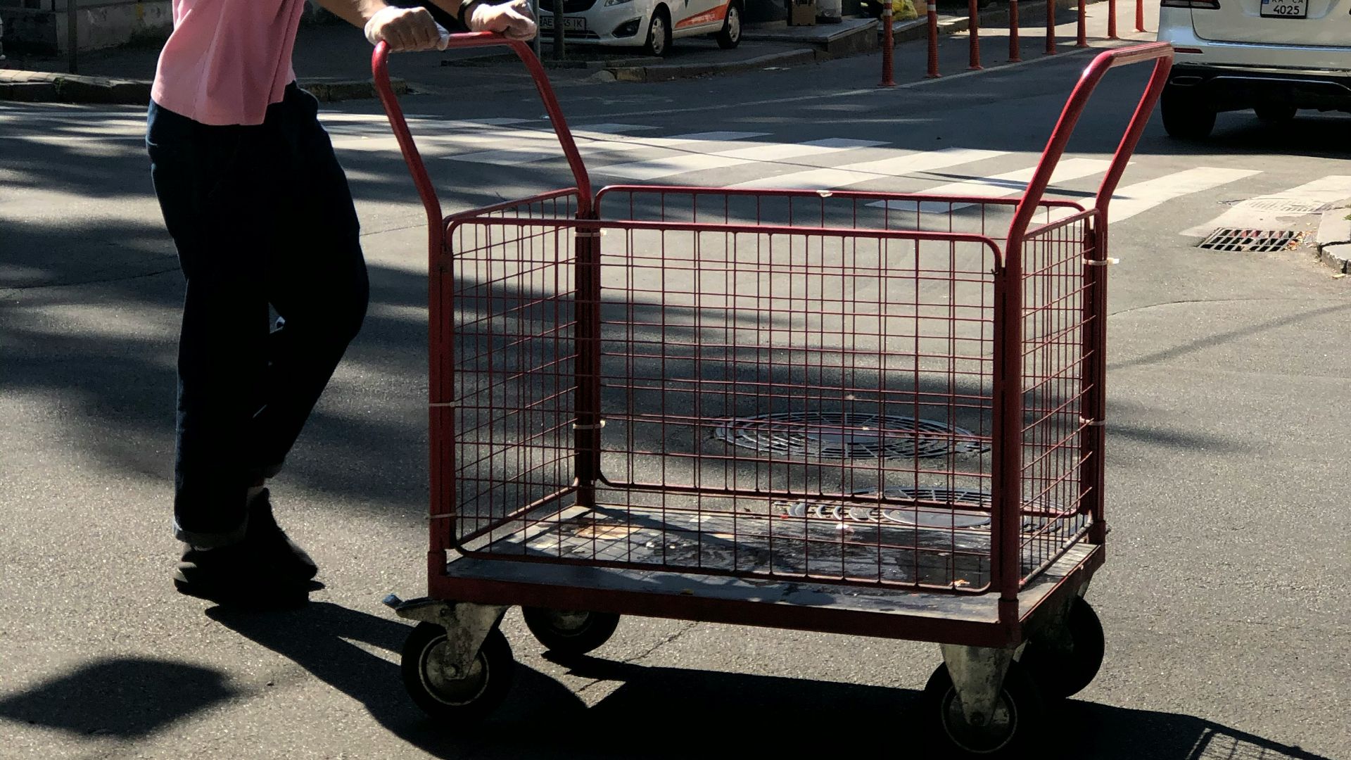 woman in white shirt and black pants holding red shopping cart