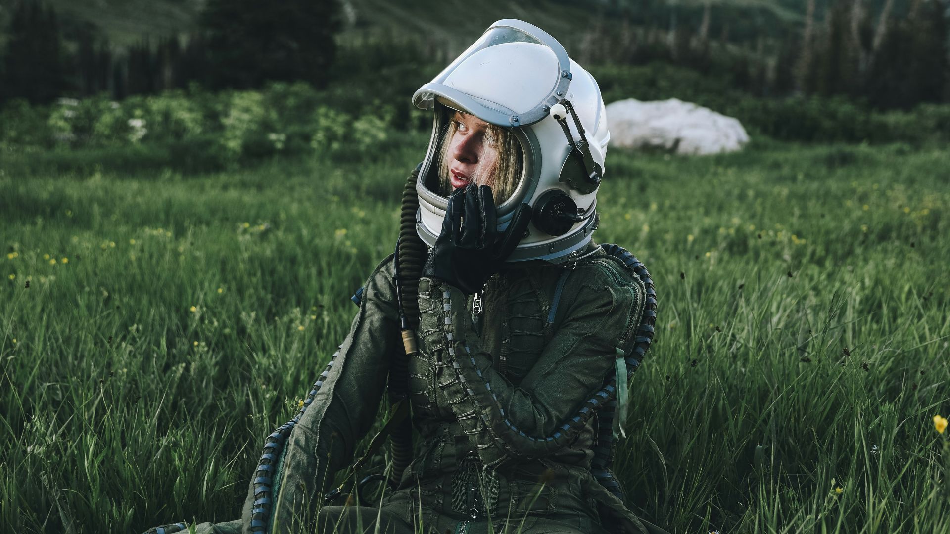 man in black jacket wearing white helmet sitting on green grass field during daytime