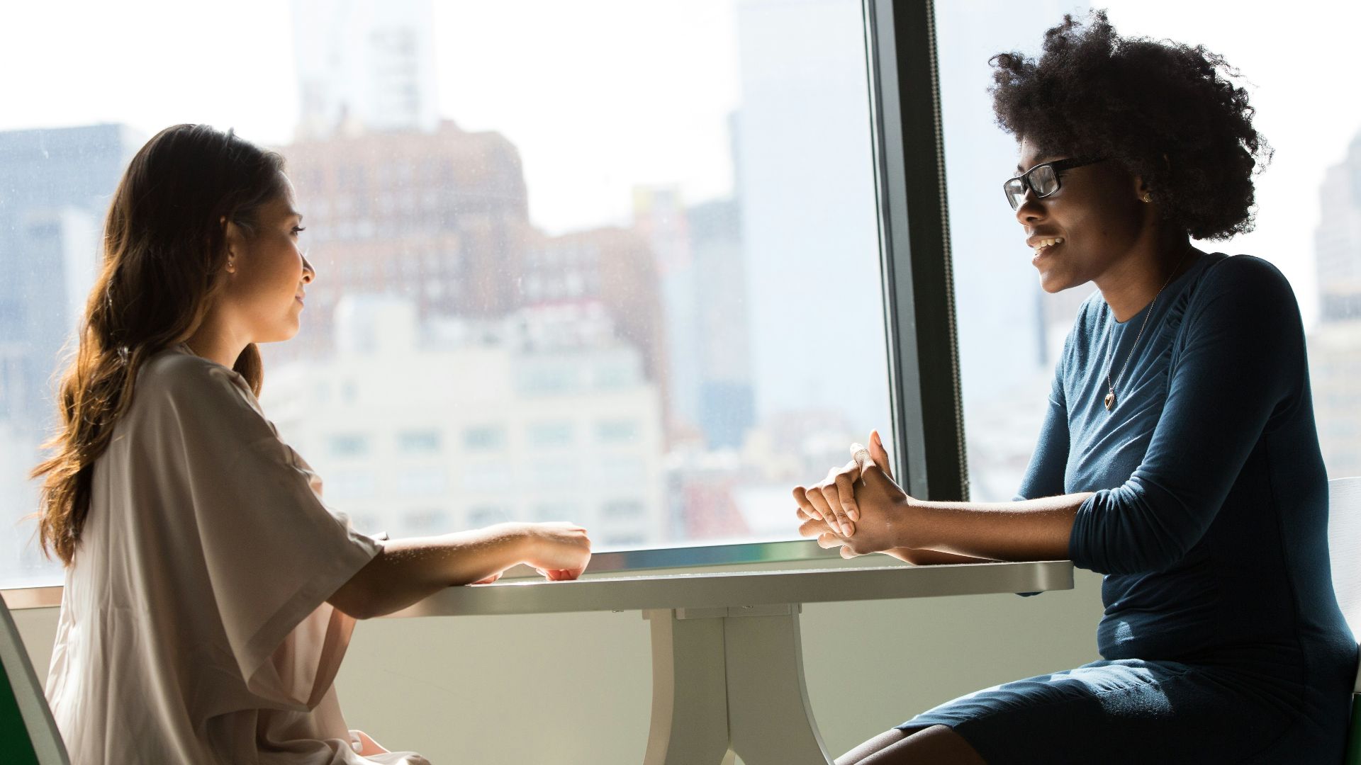 two women sitting beside table and talking