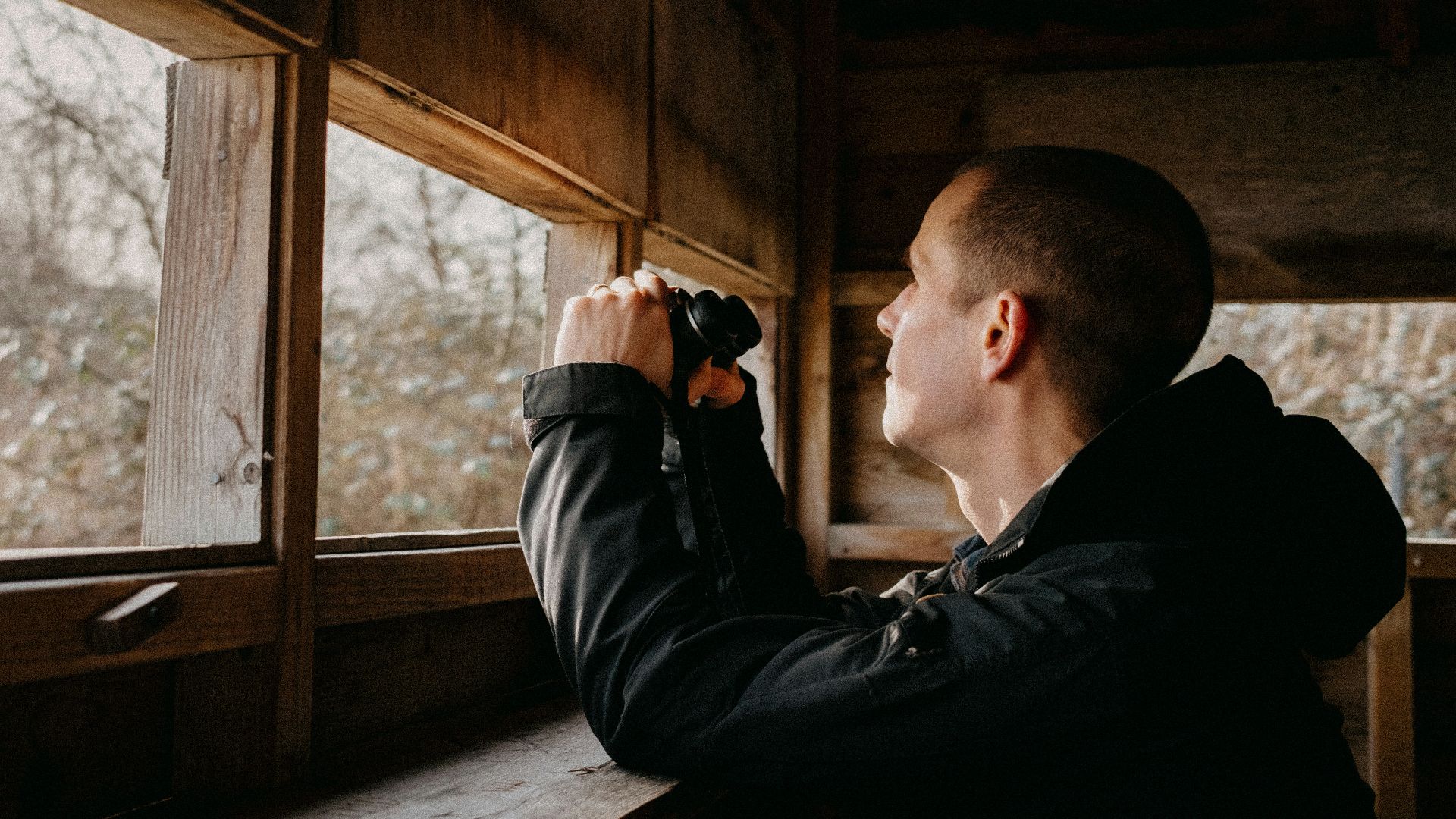 a man looking out of a window in a cabin