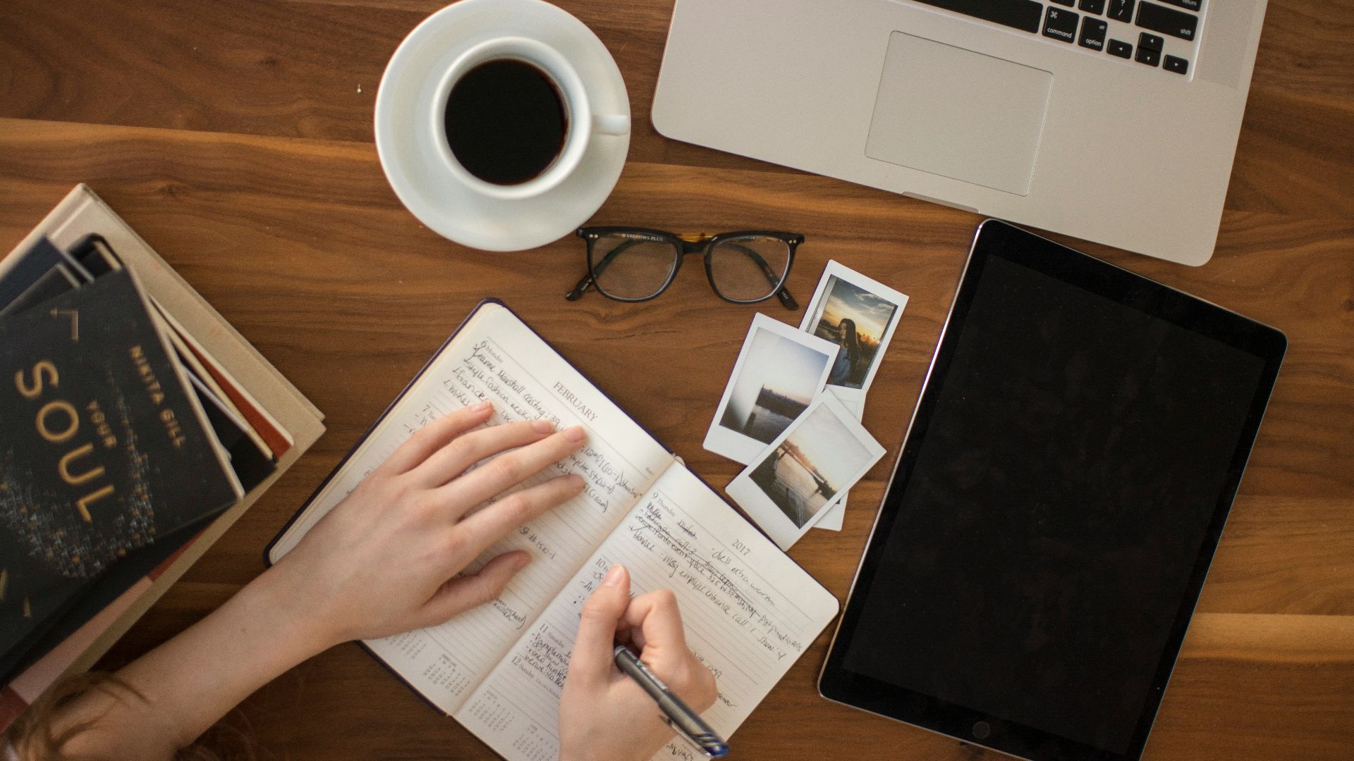 person holding ballpoint pen writing on notebook