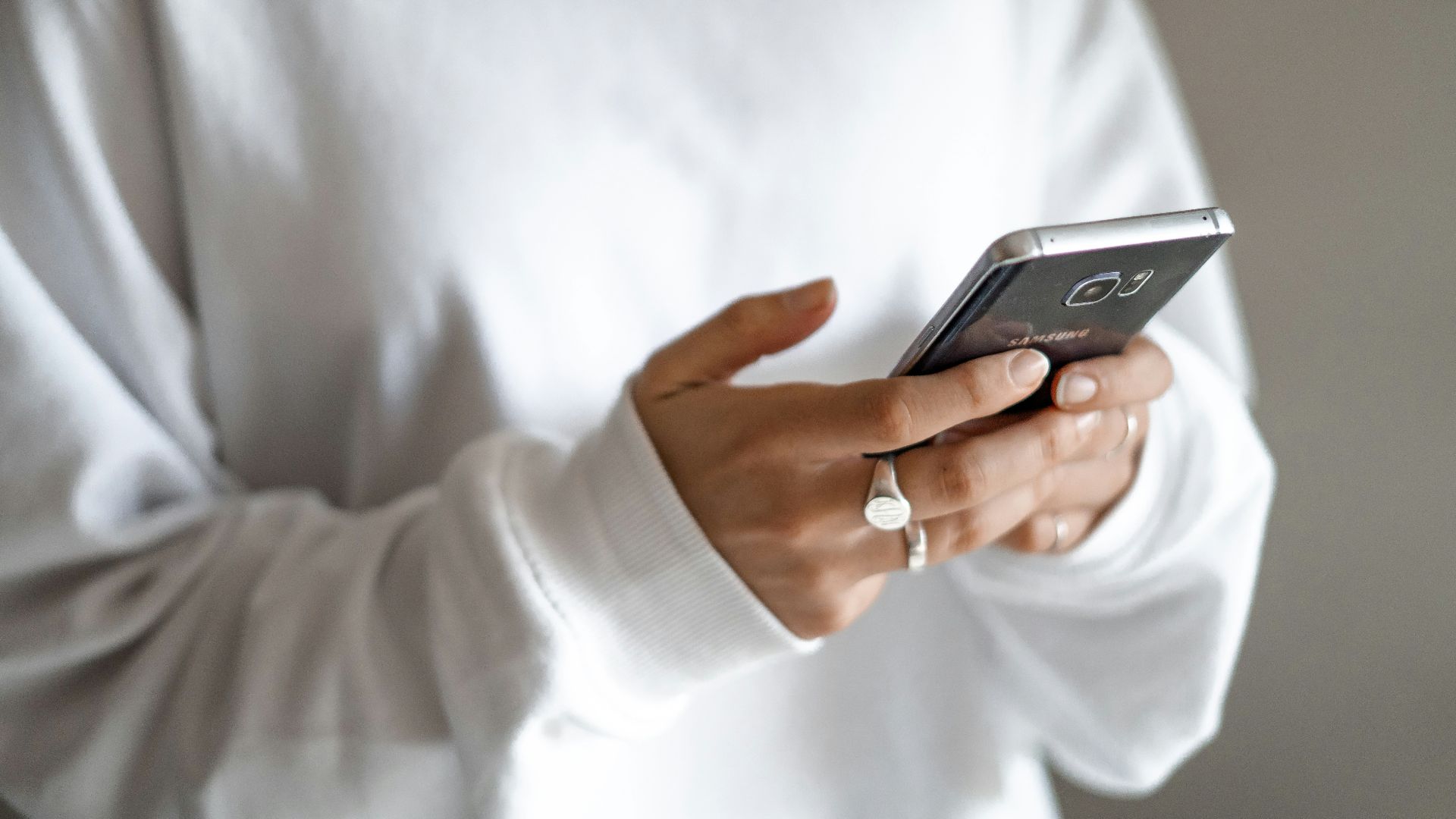 person in white long sleeve shirt holding black smartphone