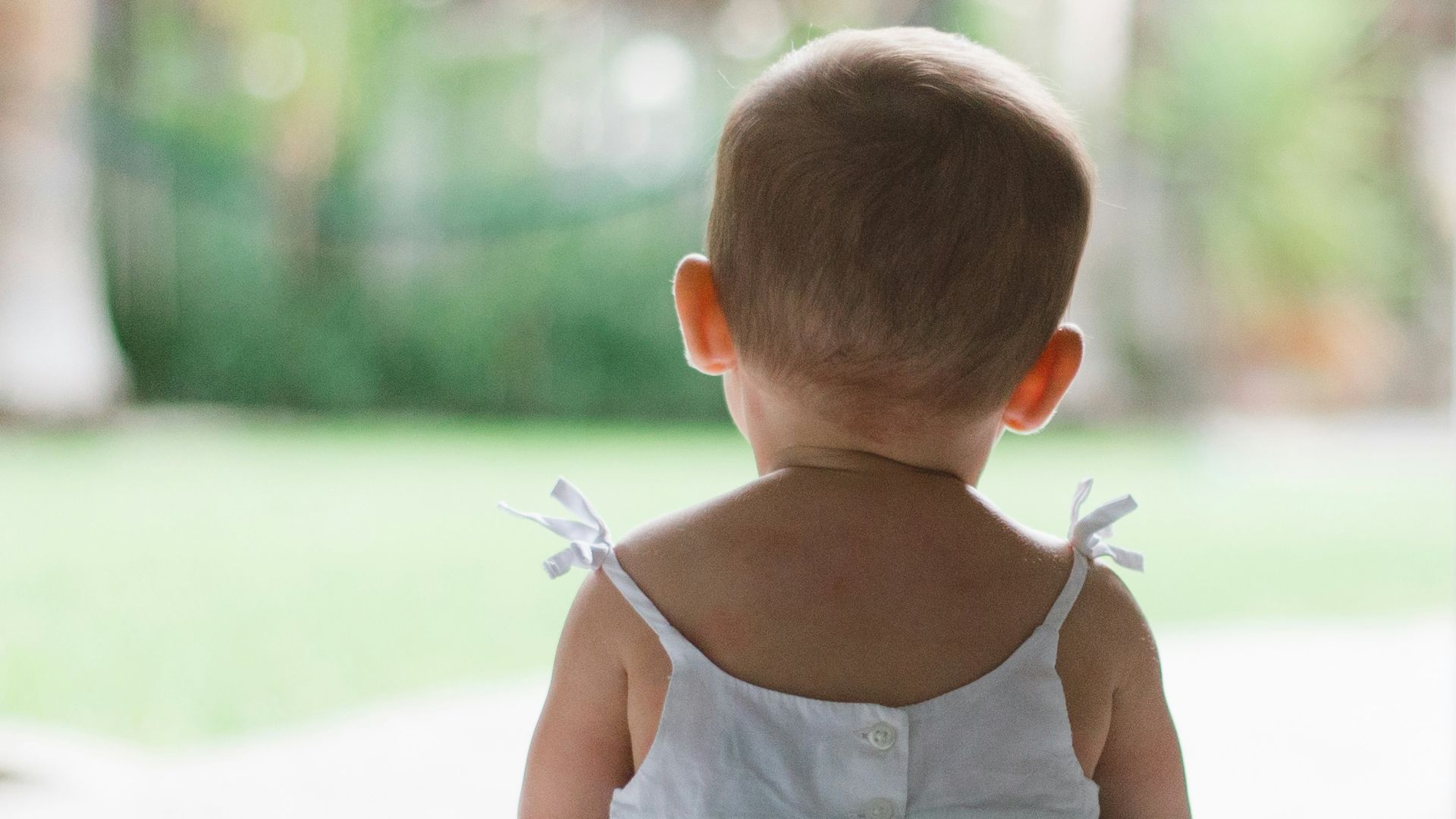 selective focus photo of toddler wearing sleeveless dress sitting on floor
