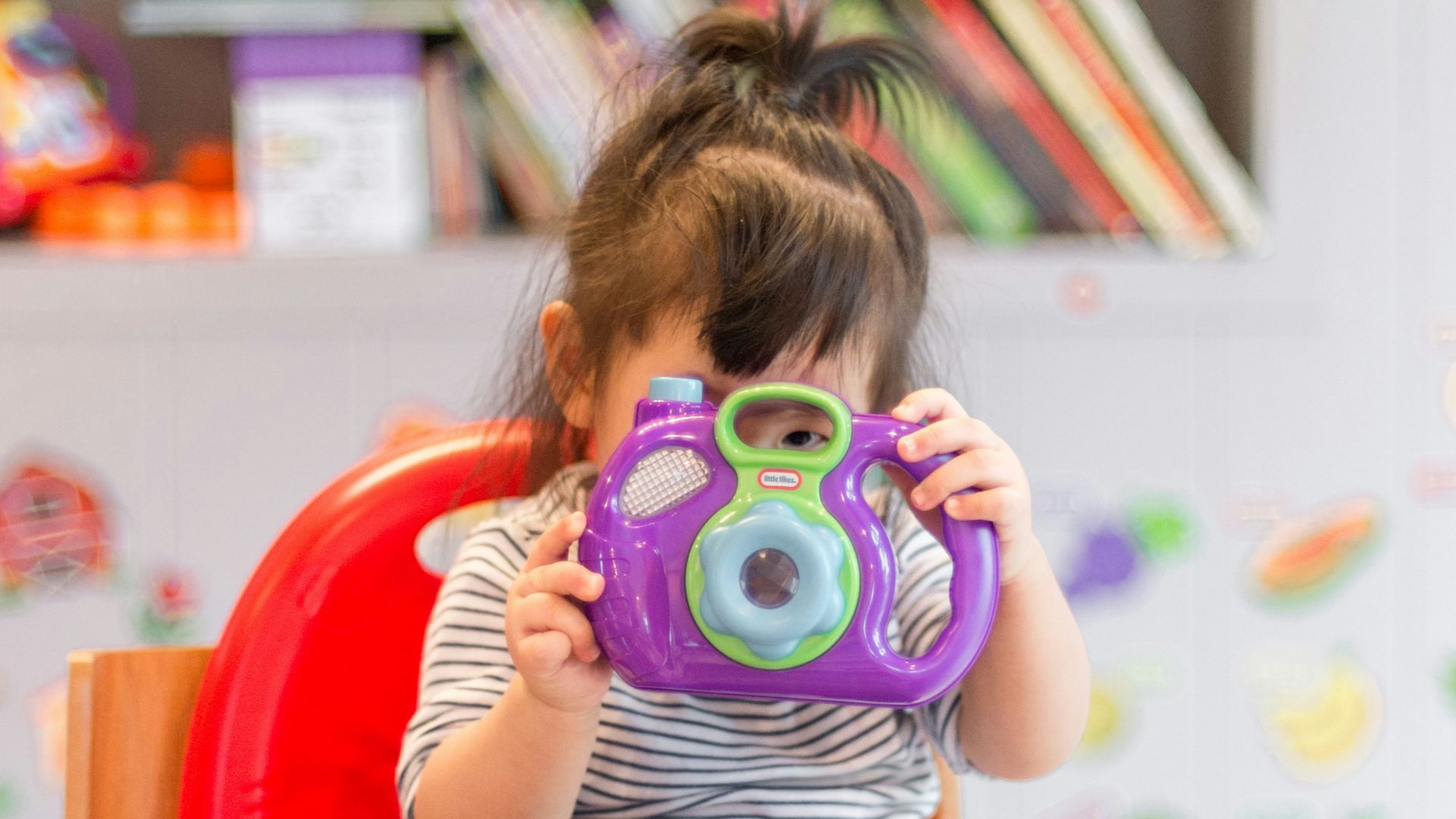 girl holding purple and green camera toy