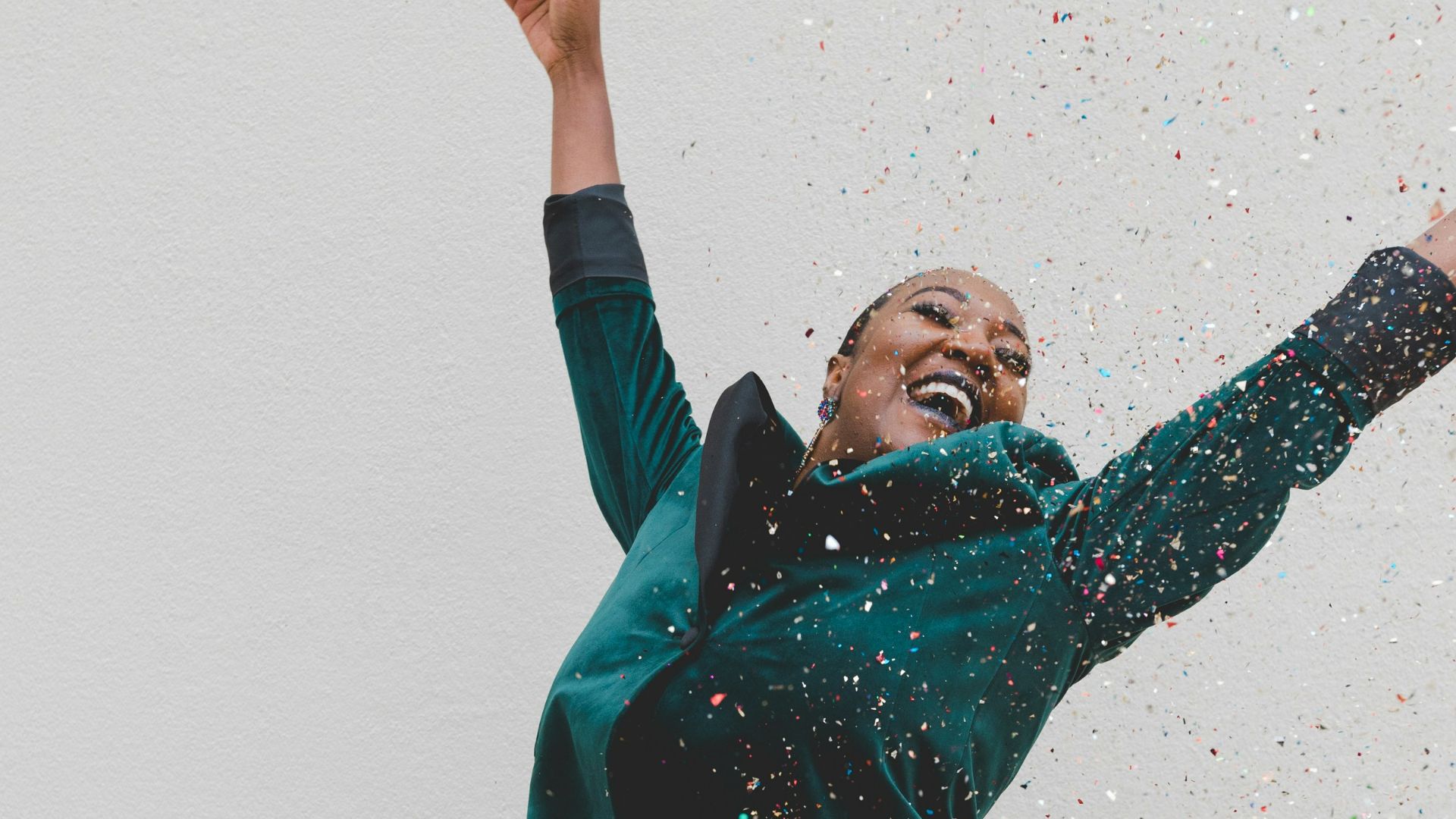 woman in green jacket raising her hands