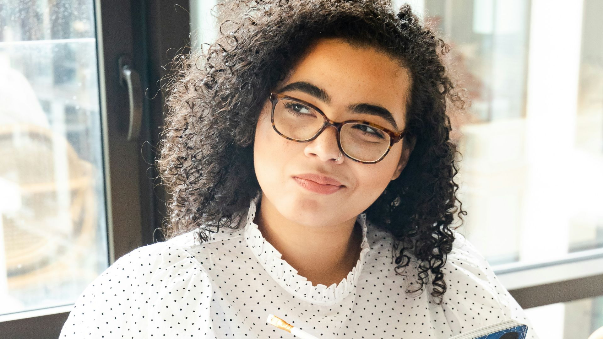 woman in white and black polka dot shirt holding blue and white book