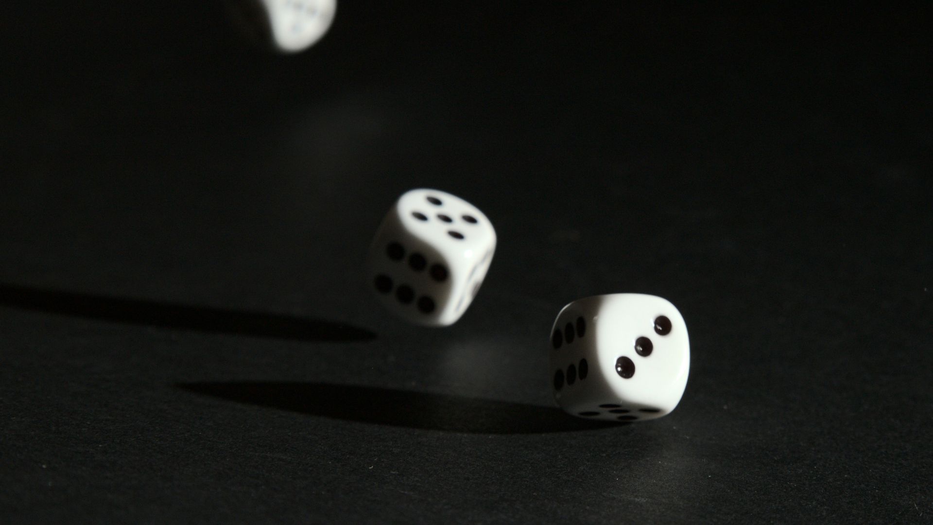 3 white dice on black surface
