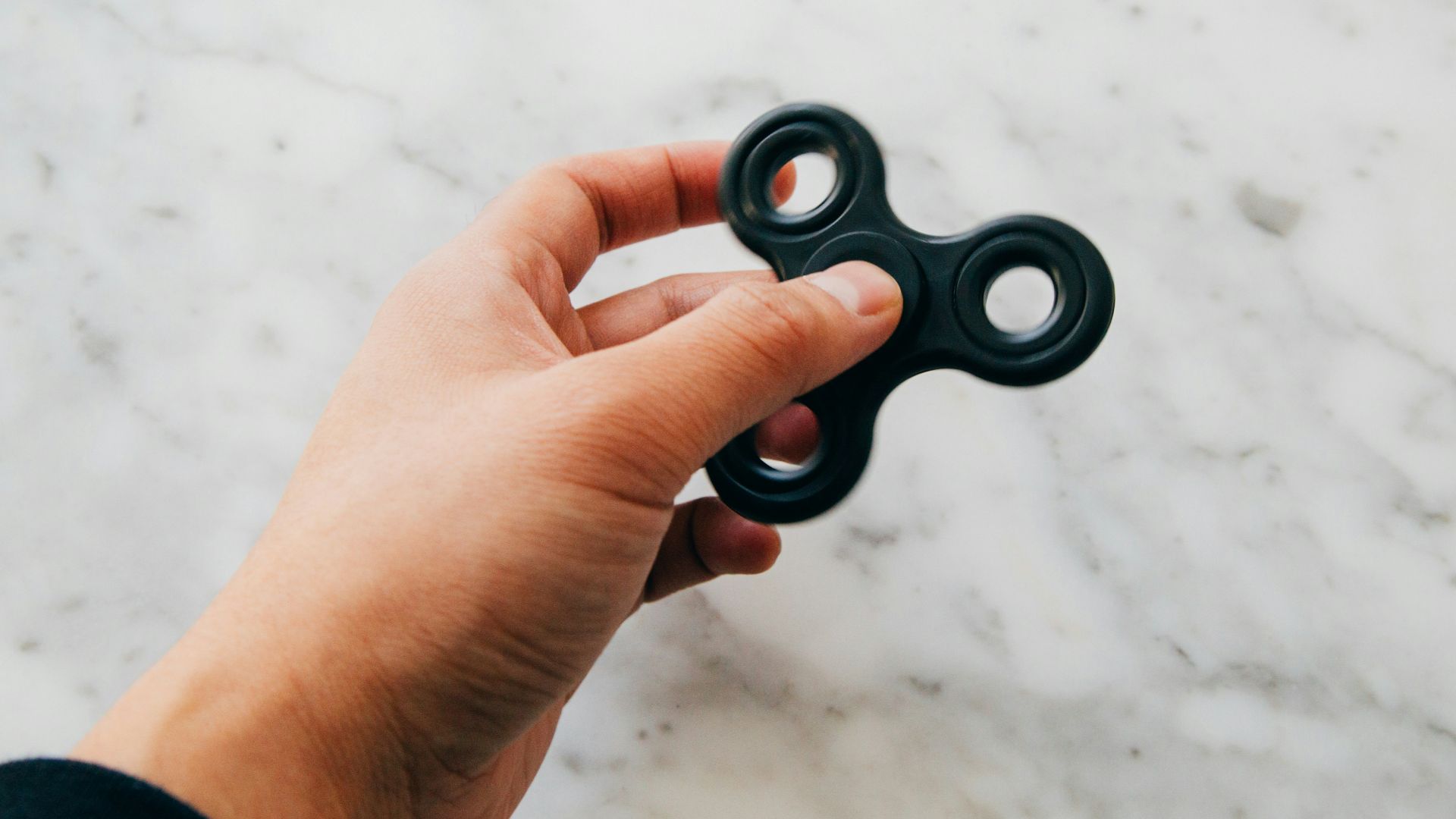 person using black fidget spinner