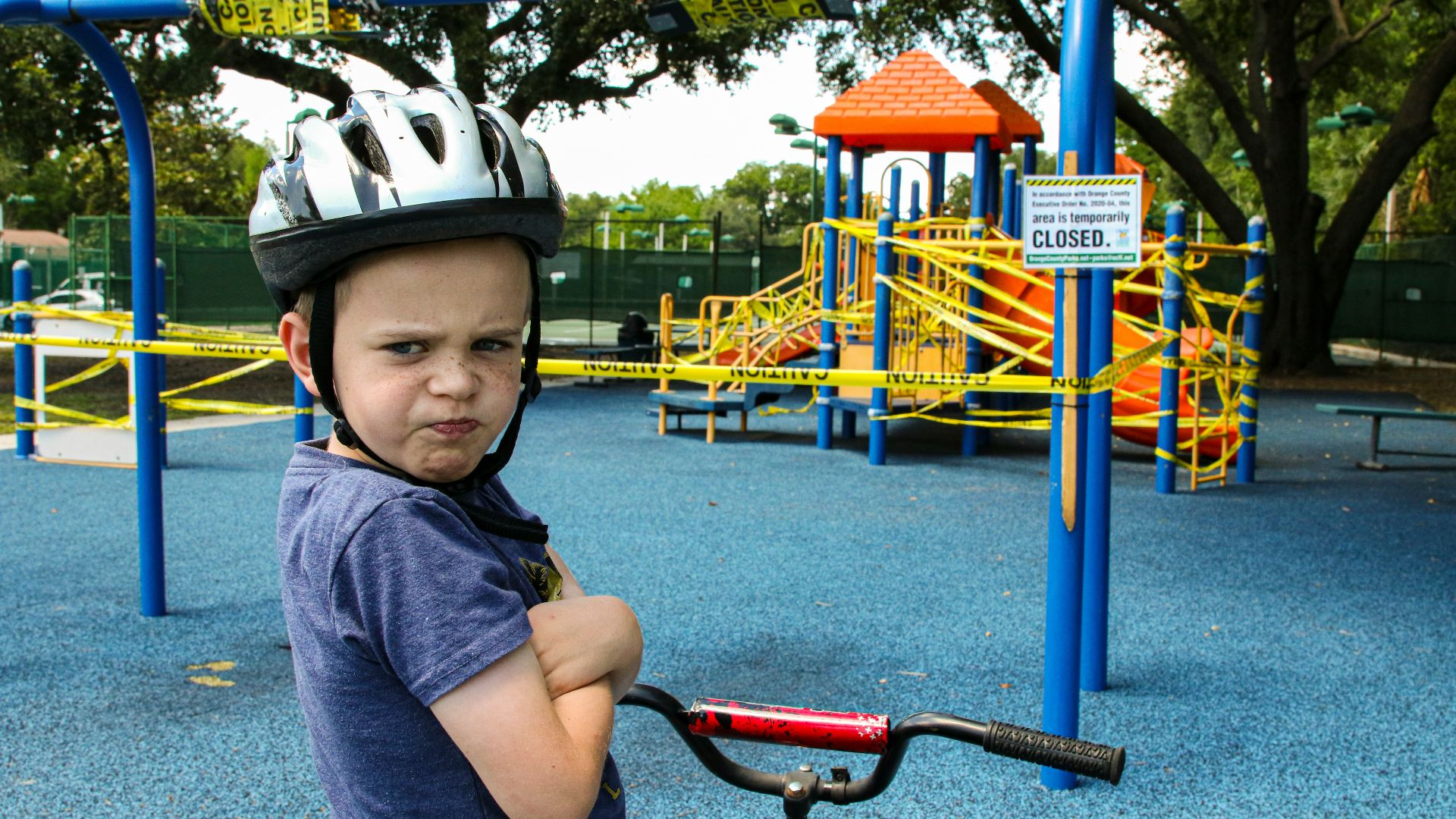 boy in blue denim vest and helmet riding red bicycle