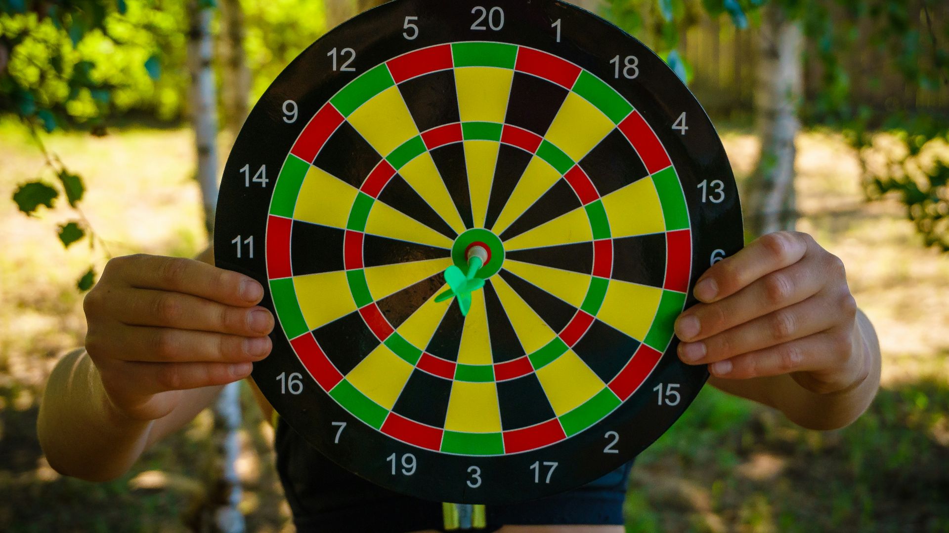 person holding black red yellow and green round analog clock