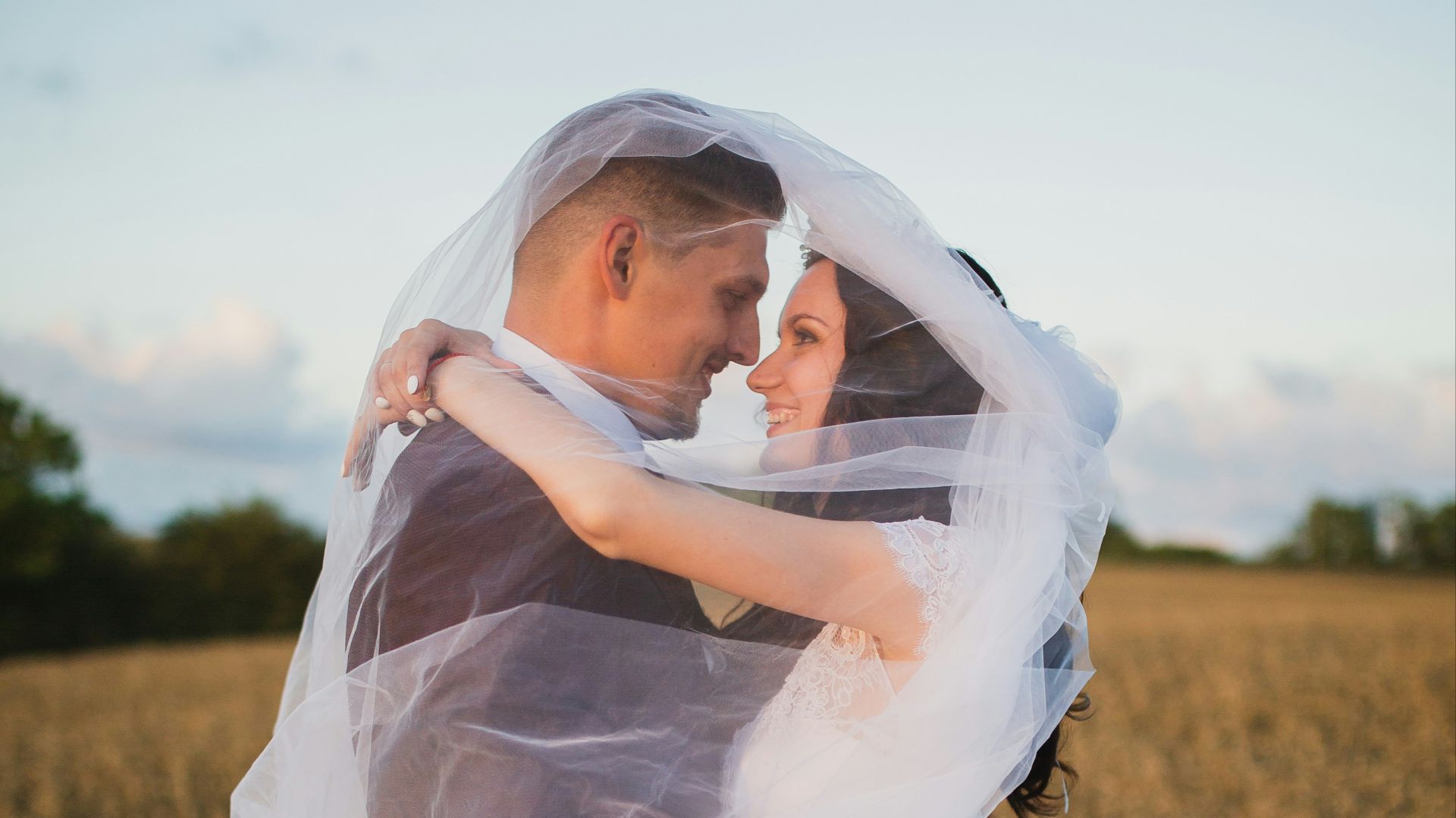 smiling newly wed couple about to kiss in green field