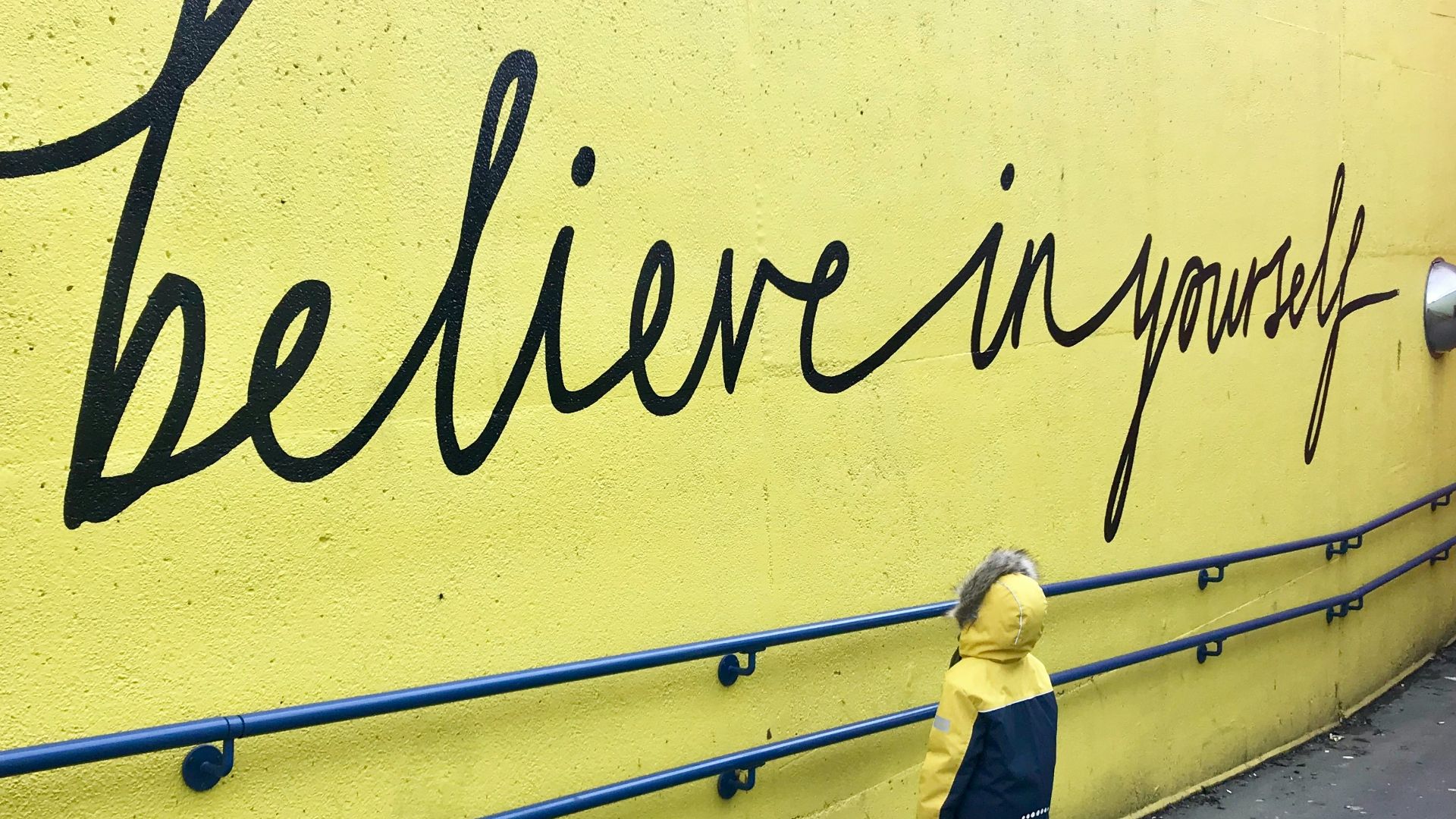 toddler looking at believe in yourself graffiti