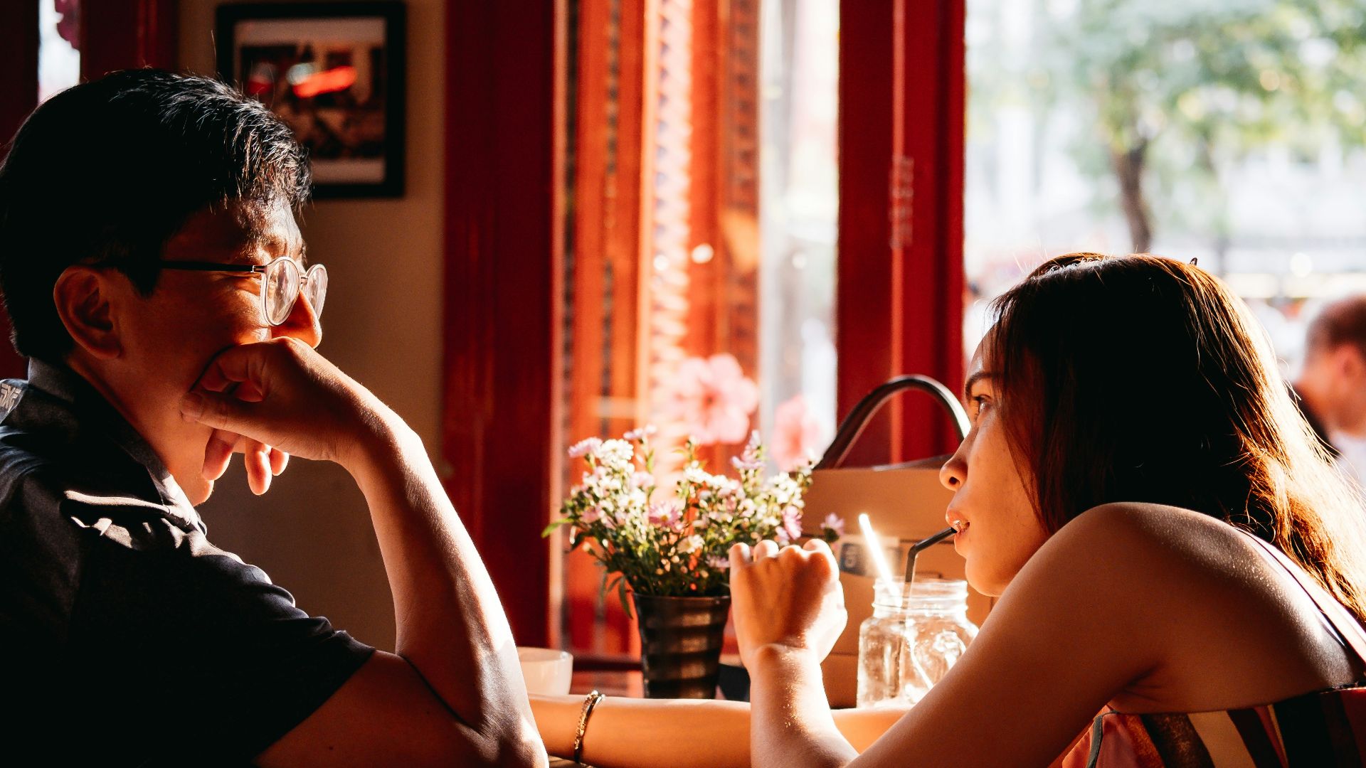 man wearing black collared top sitting on chair in front of table and woman wearing multicolored top