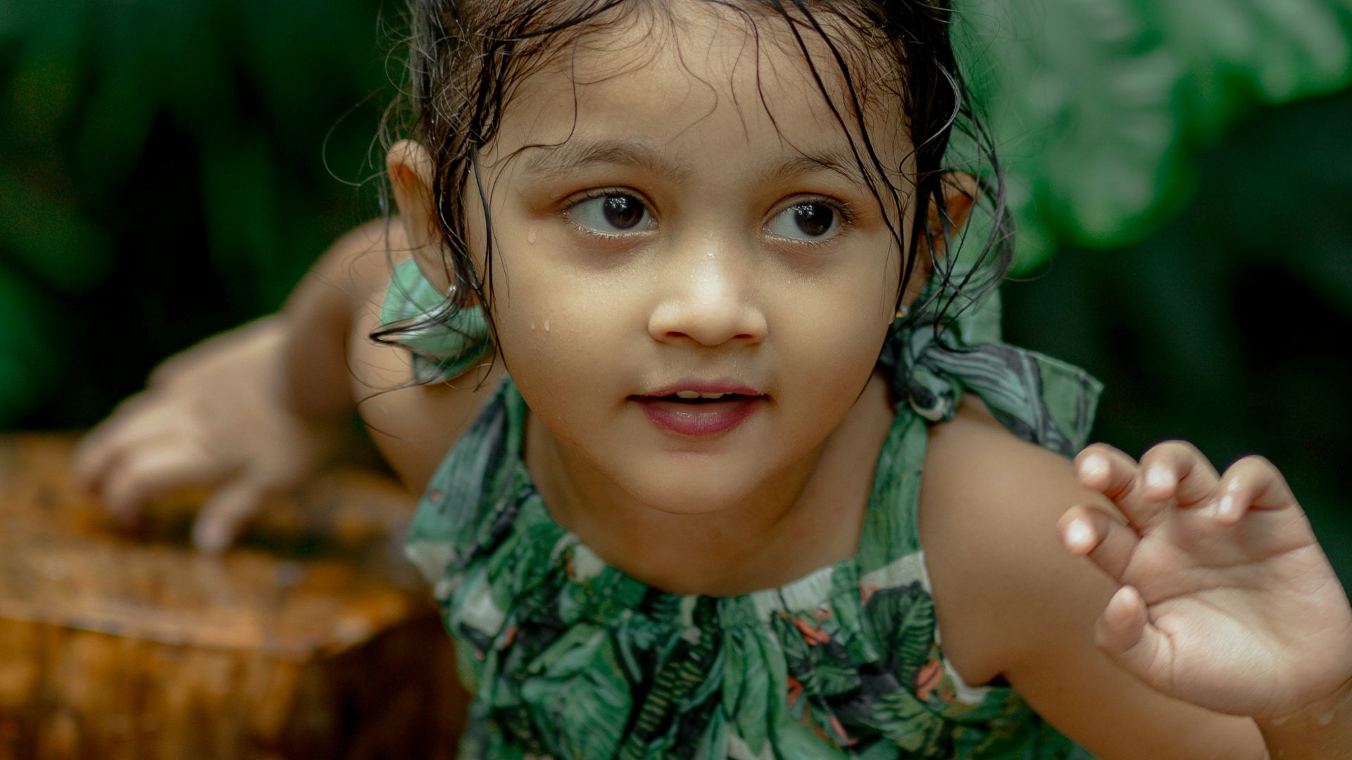 a little girl standing next to a tree stump