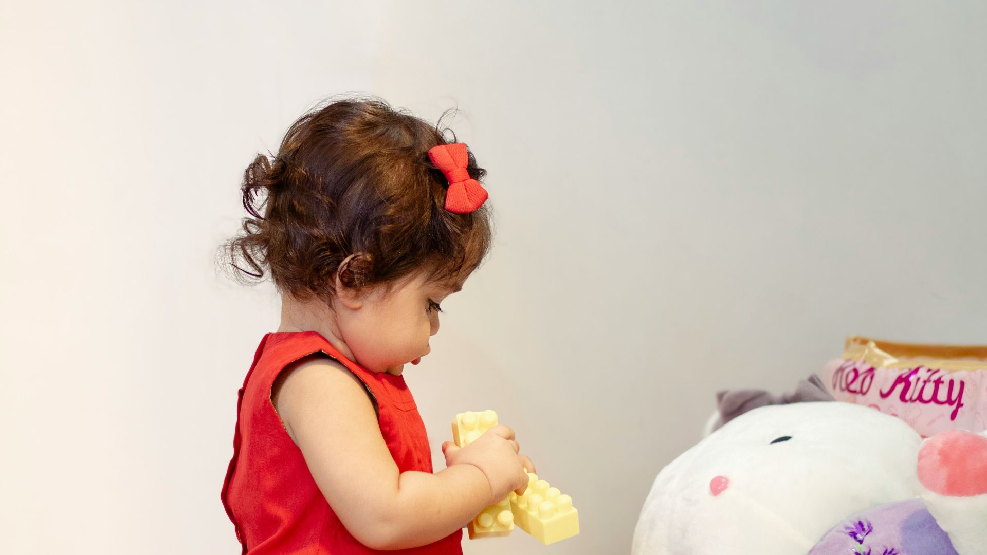 a little girl in a red dress playing with a stuffed animal