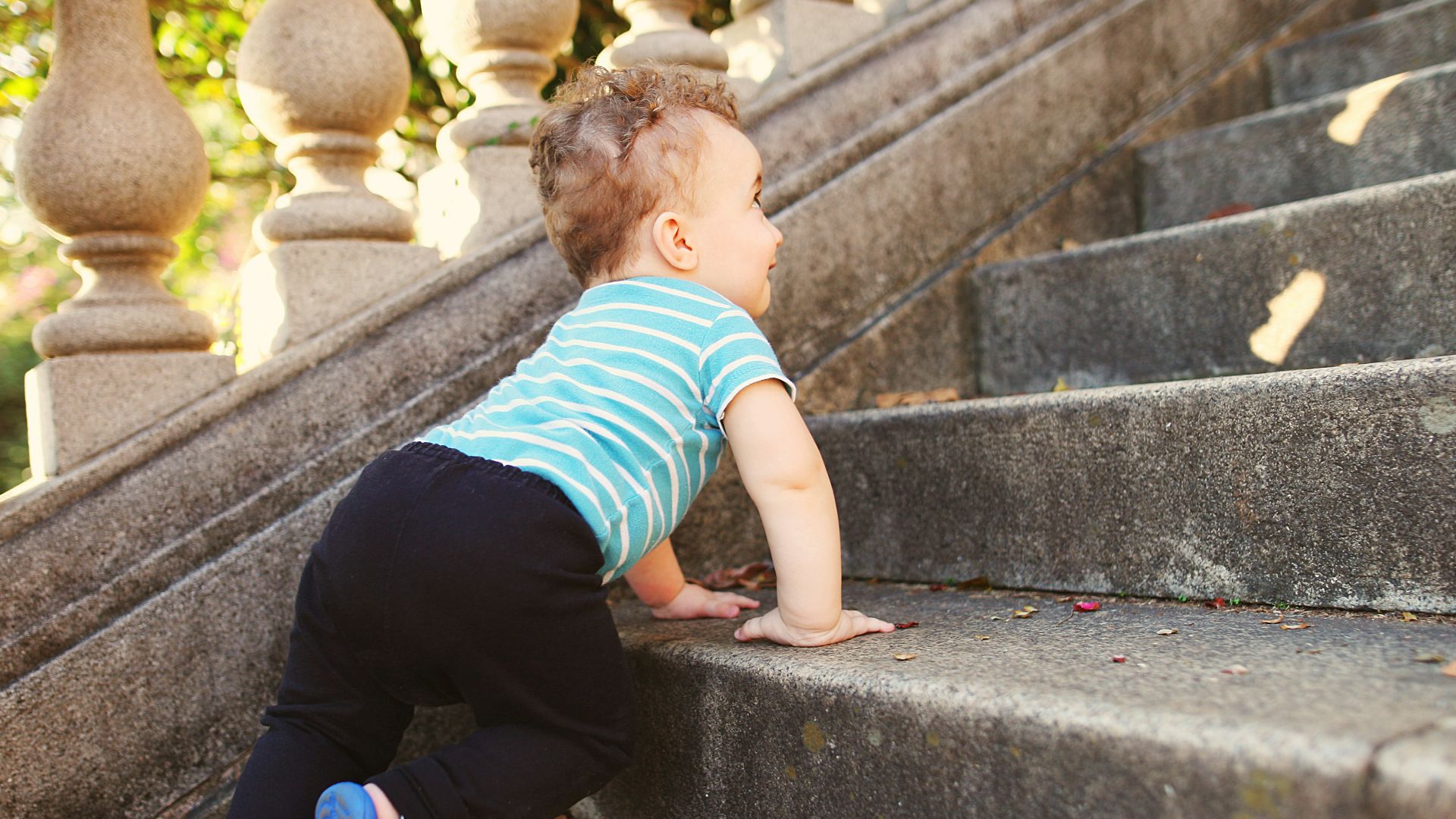 boy in green and white striped t-shirt and black pants sitting on concrete stairs during