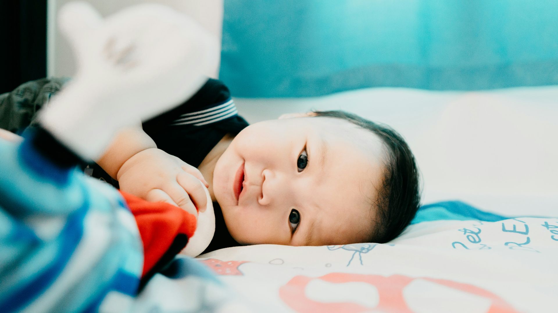 baby in black and white shirt lying on bed