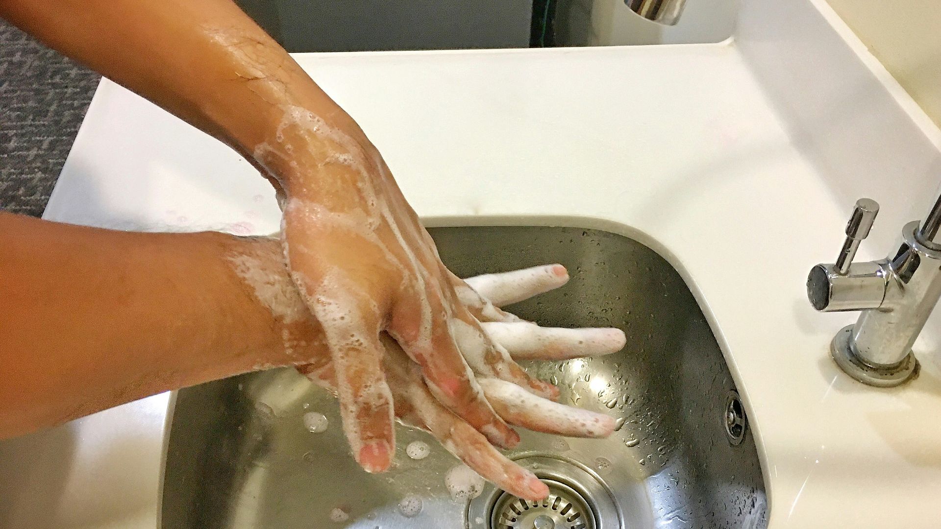 person washing hands on sink