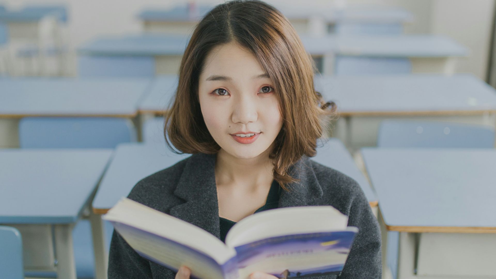 woman reading book sitting on chair in room