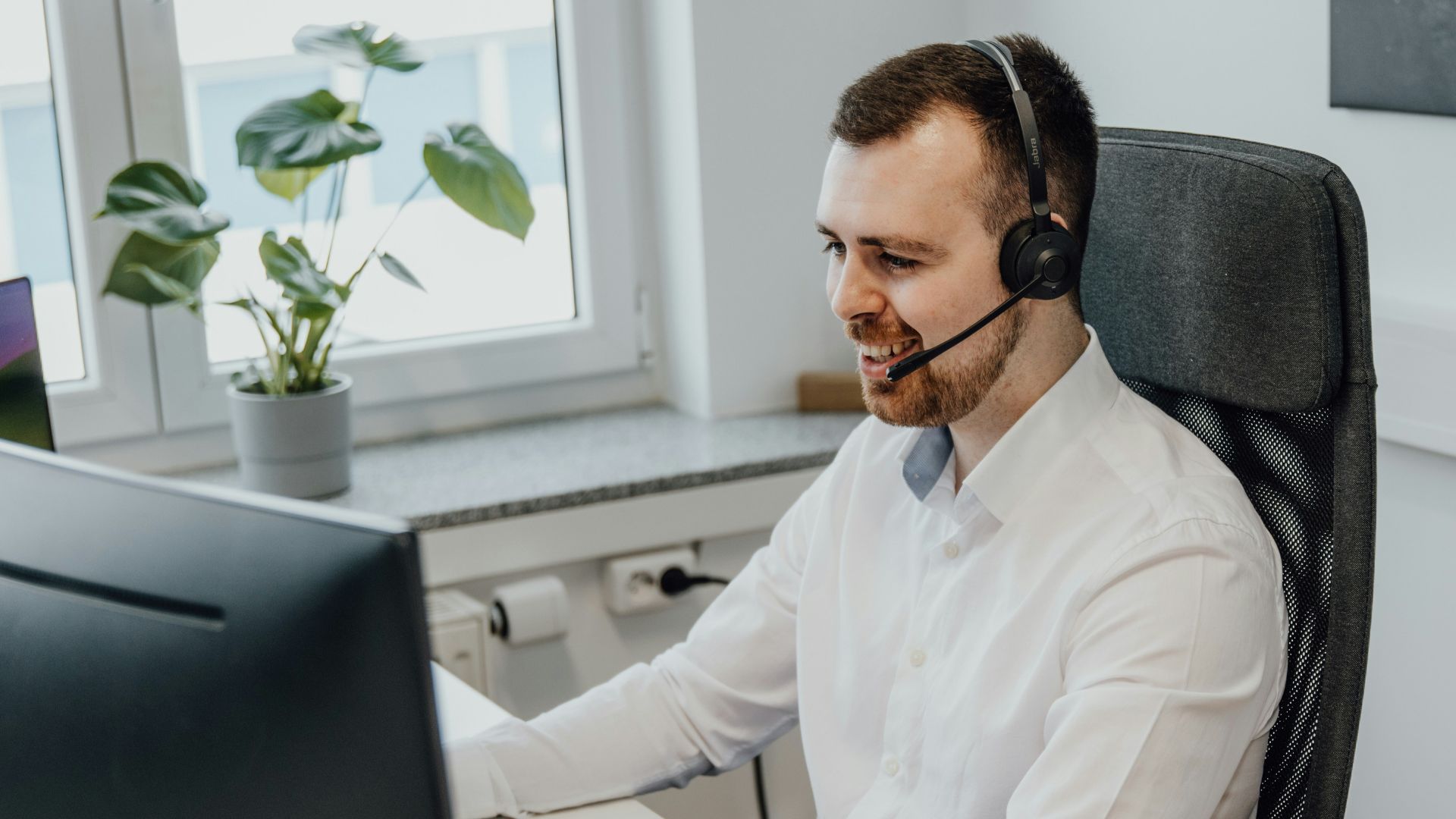 a man wearing a headset sitting in front of a computer