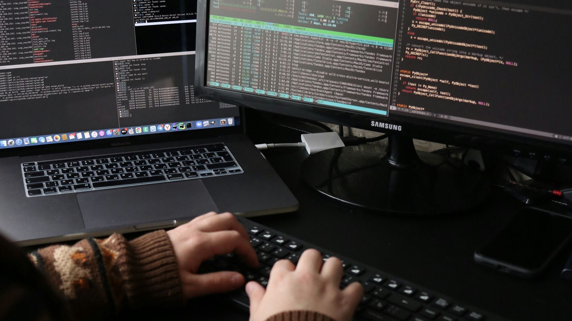 a person sitting at a desk with a laptop and a computer monitor