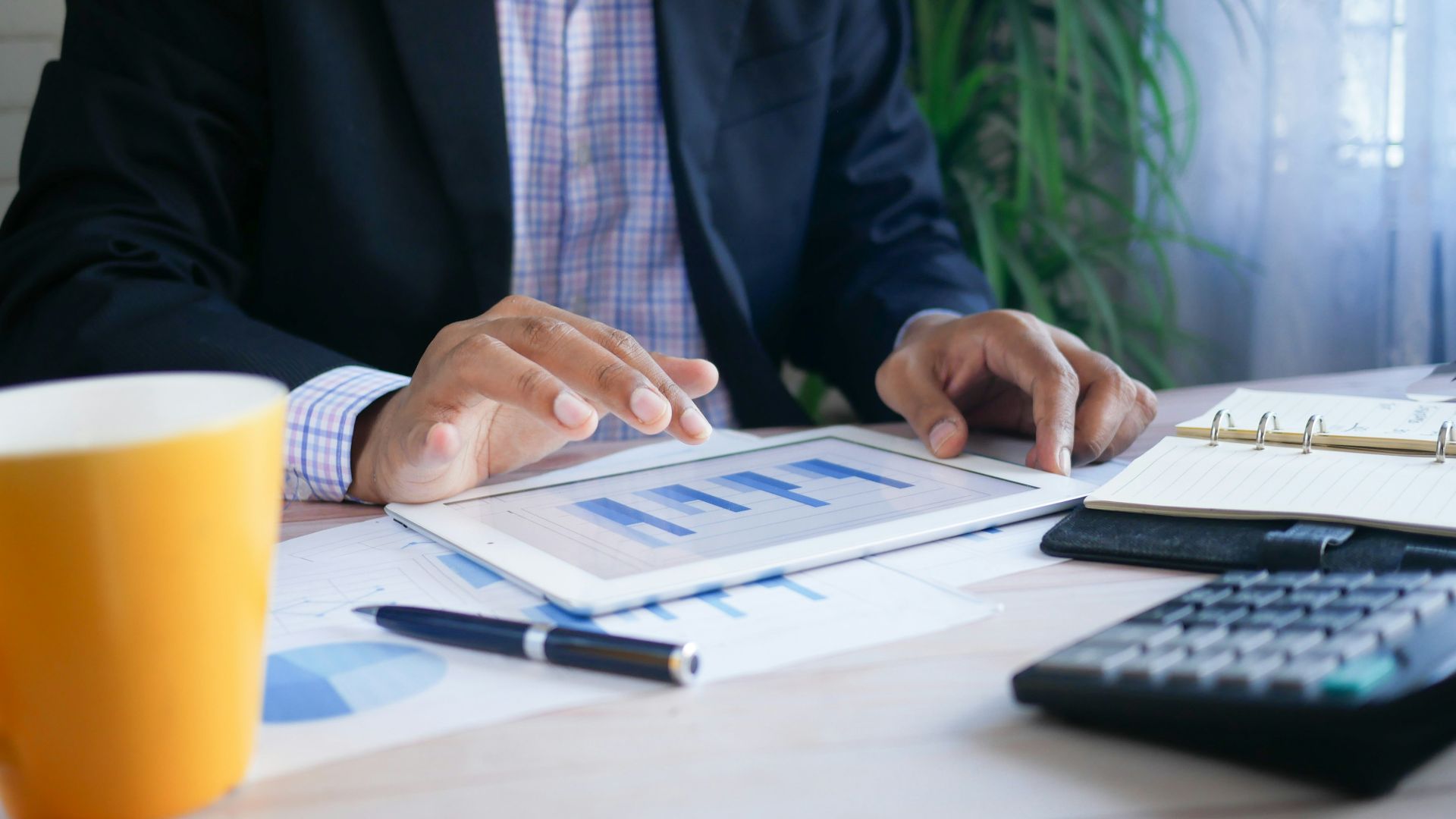 person in black suit jacket holding white tablet computer