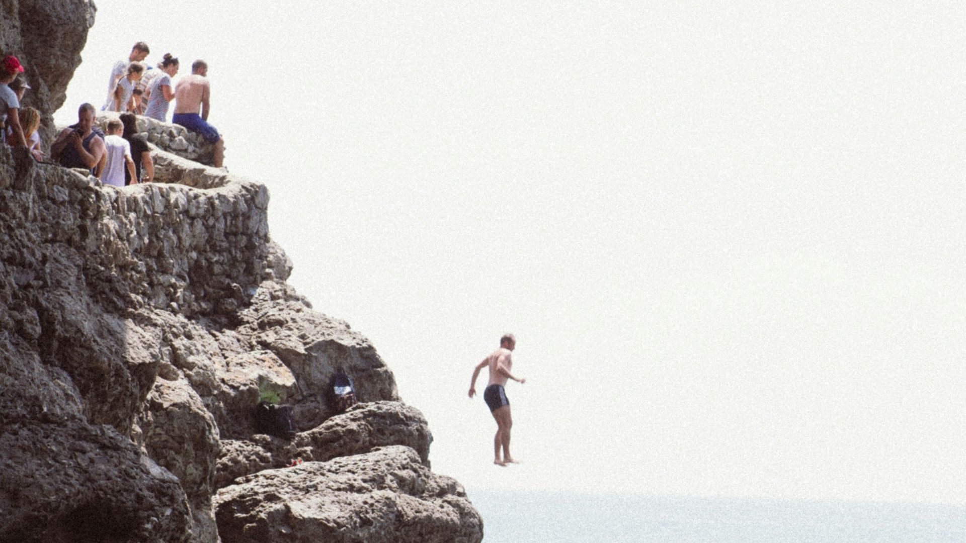 people standing on rock formation near sea during daytime