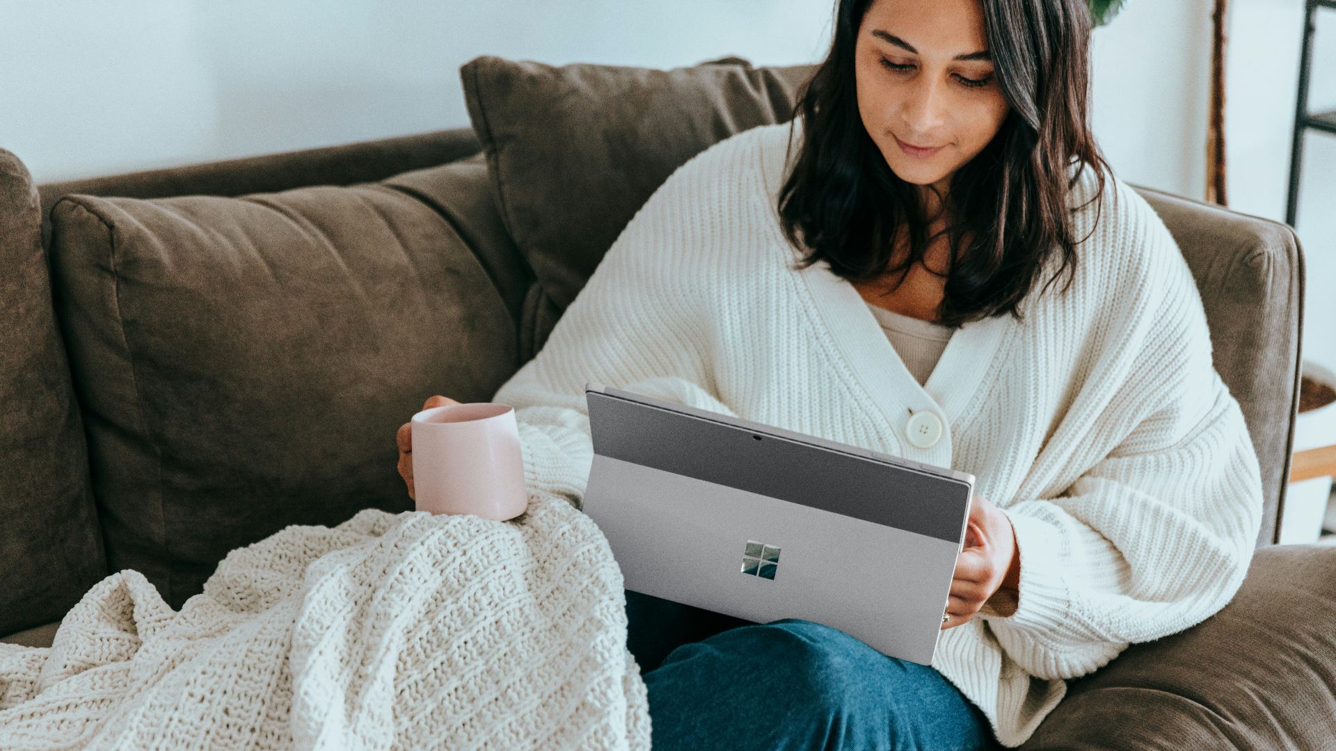 a woman sitting on a couch holding a laptop