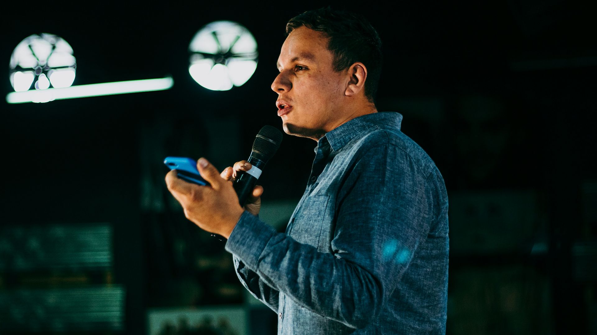 man in blue denim jacket holding microphone