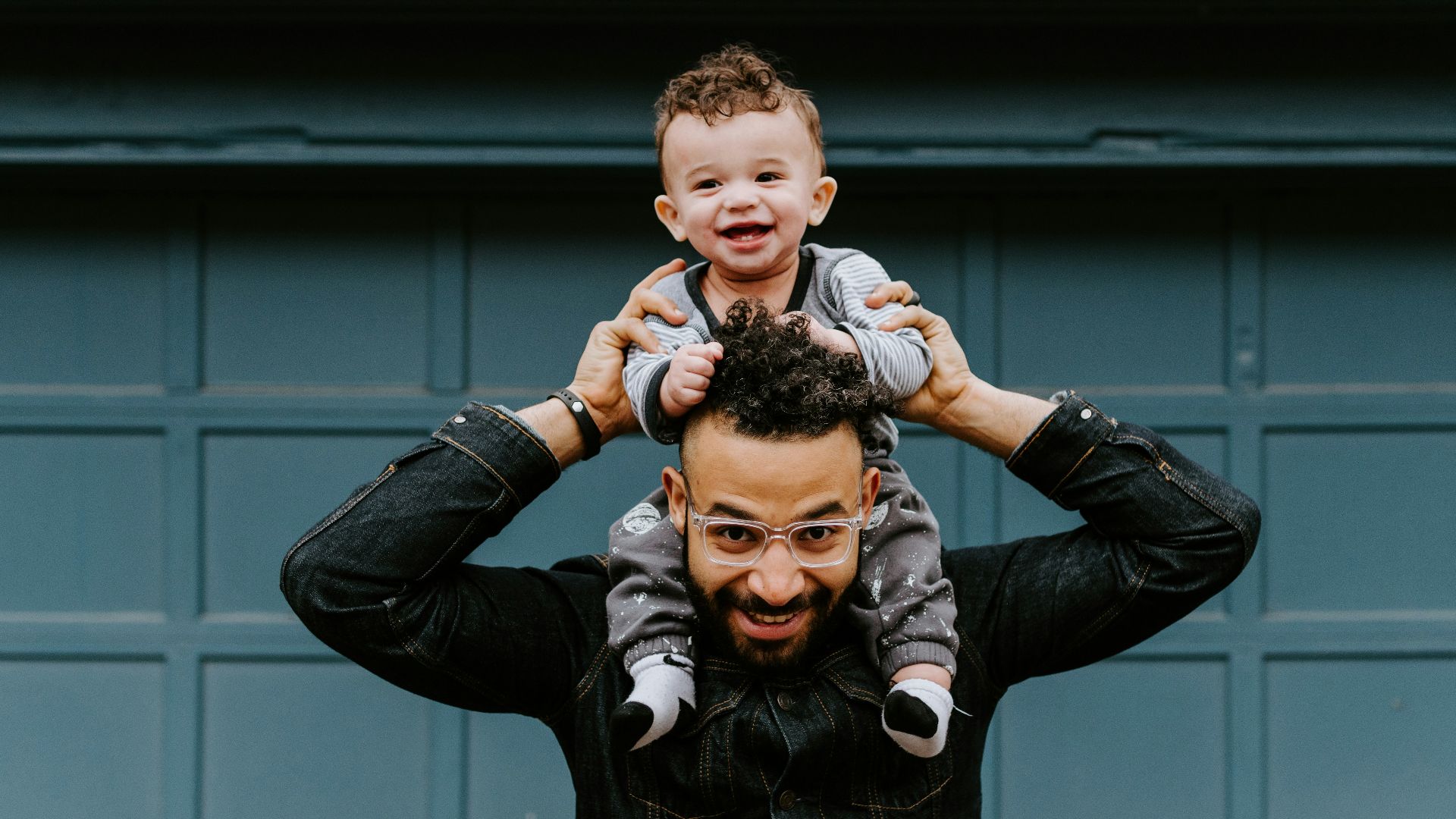 man in black leather jacket carrying boy in black leather jacket