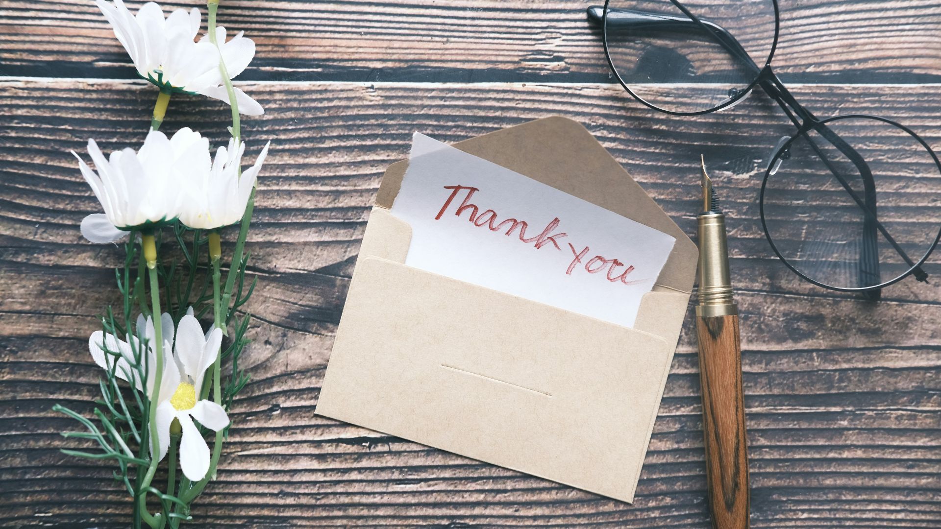a thank you note sitting on top of a table next to a pair of glasses