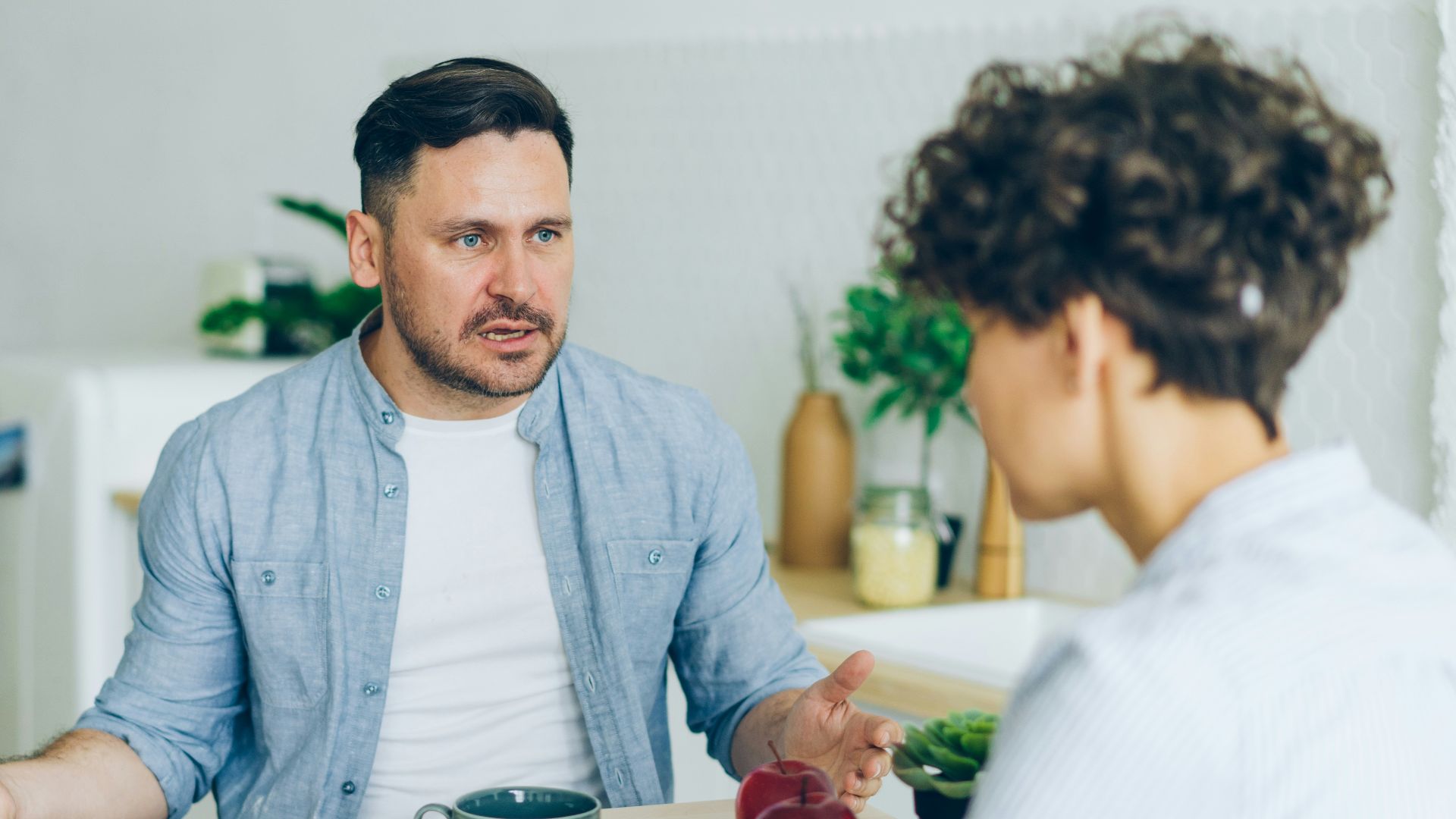 a man sitting at a table talking to a woman
