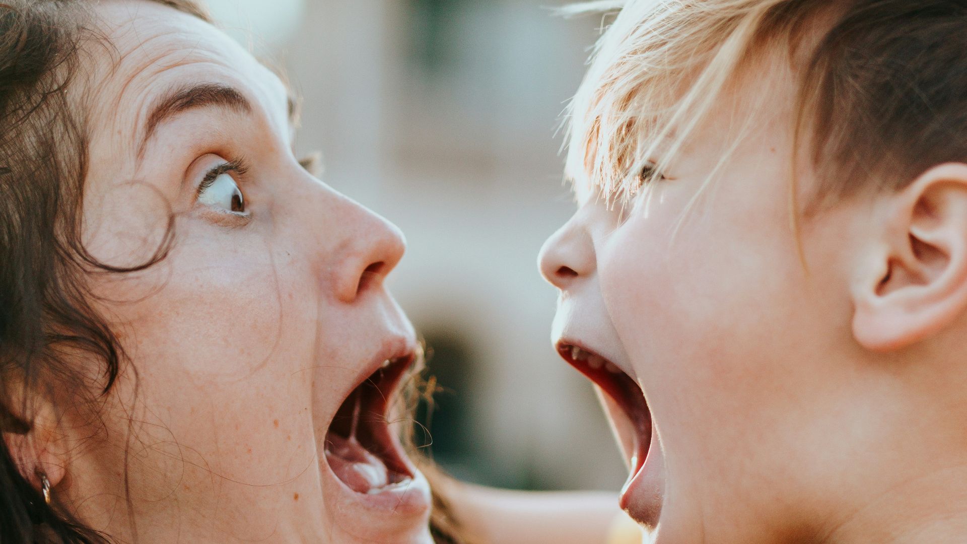 woman in black sweater kissing girl in yellow shirt