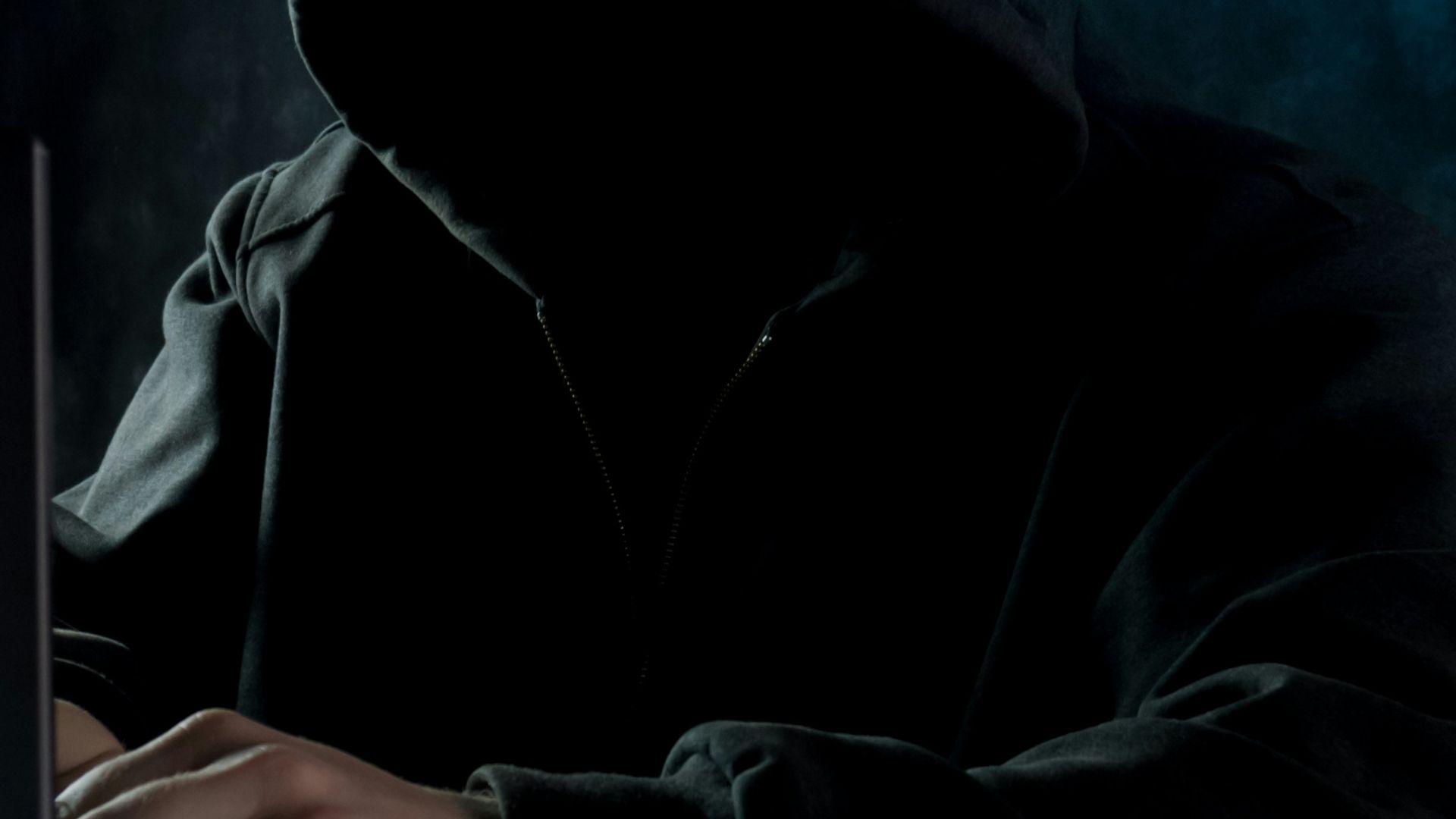 a man in a hoodie using a laptop computer