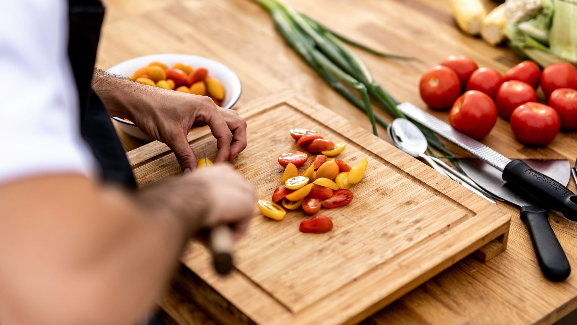 a person cutting up vegetables on a cutting board