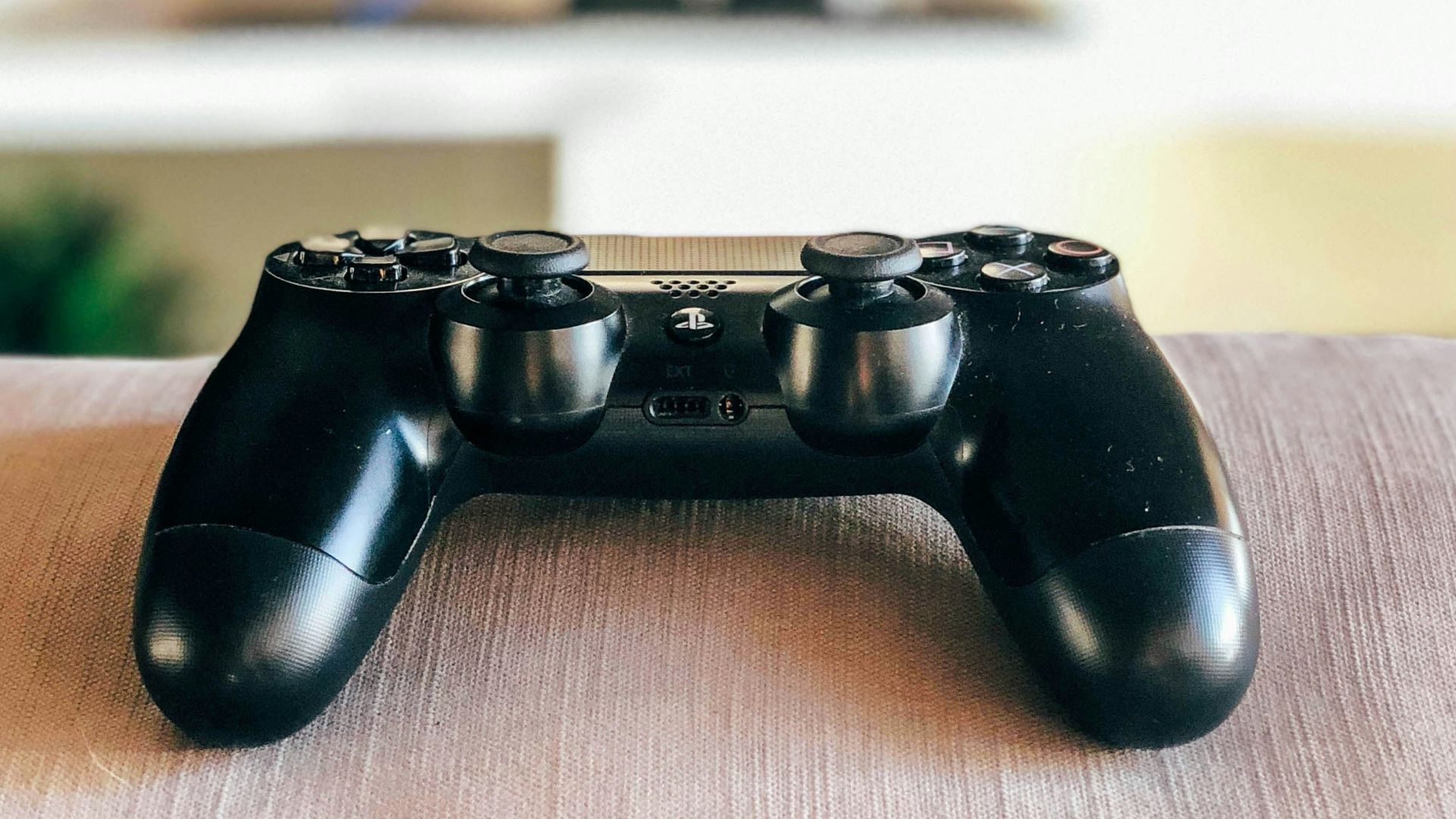 dept of field photography of black Sony PS4 DualShock 4 controller on grey cloth