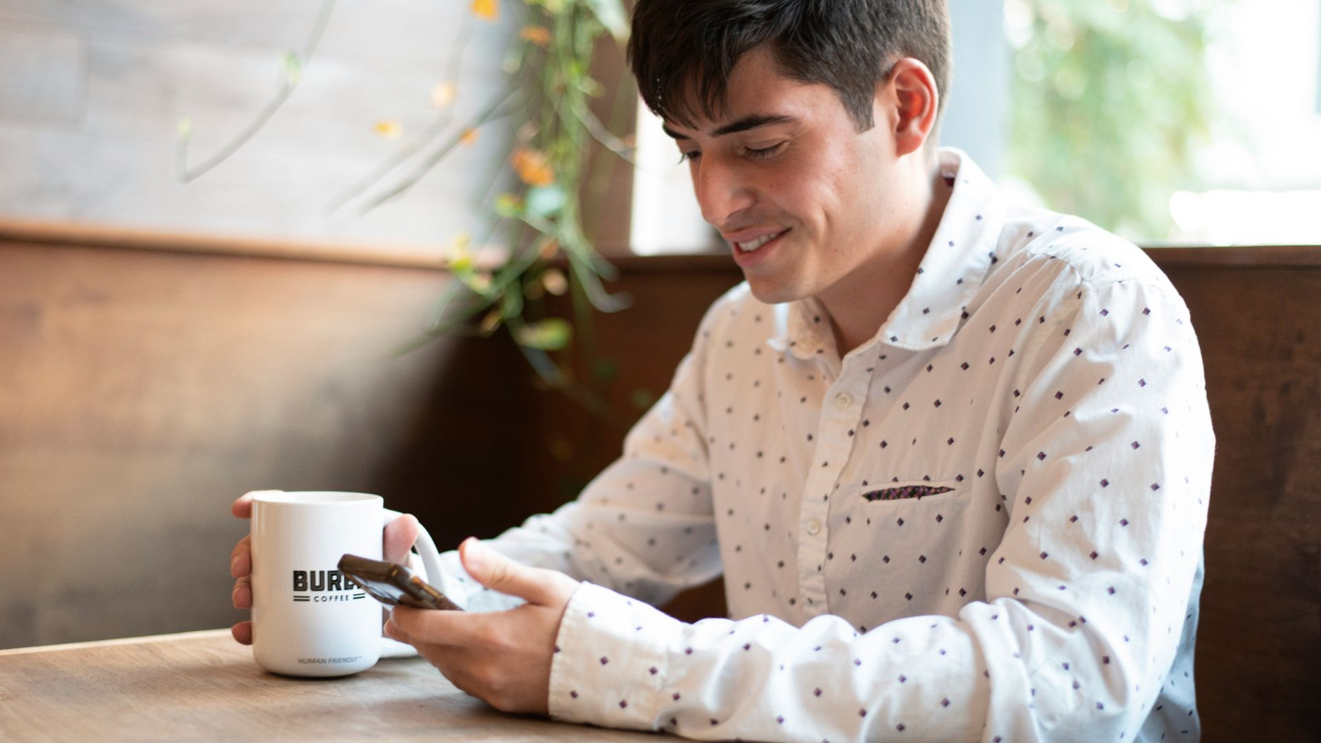 a man sitting at a table looking at his cell phone